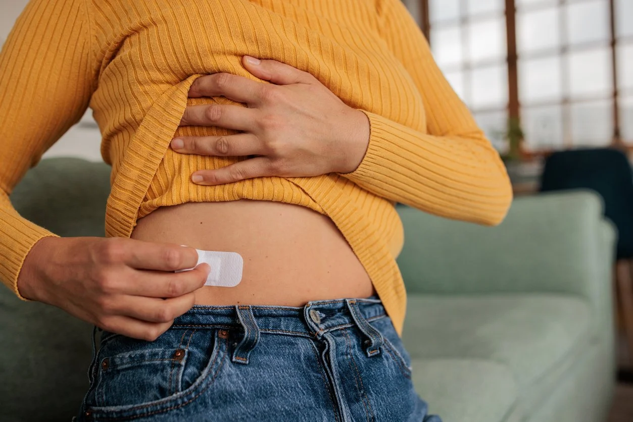 Woman applying HRT patch to abdomen