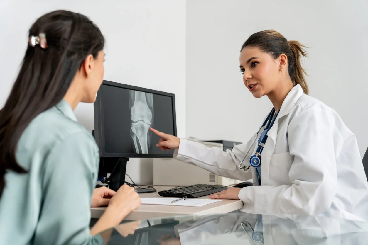 Doctor in her office looking at a knee x-ray with a female patient
