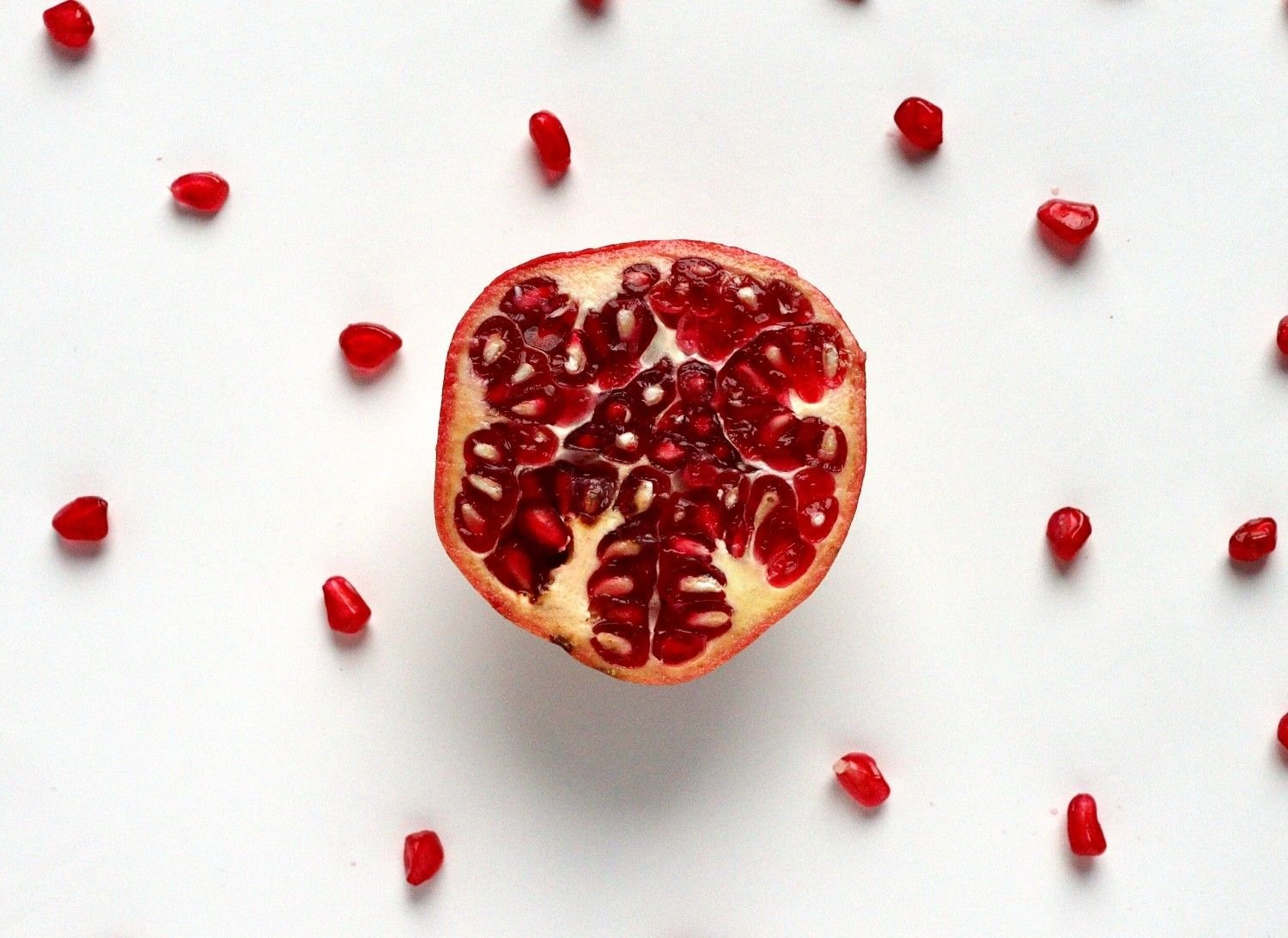 Fresh pomegranate cut in half with scattered seeds