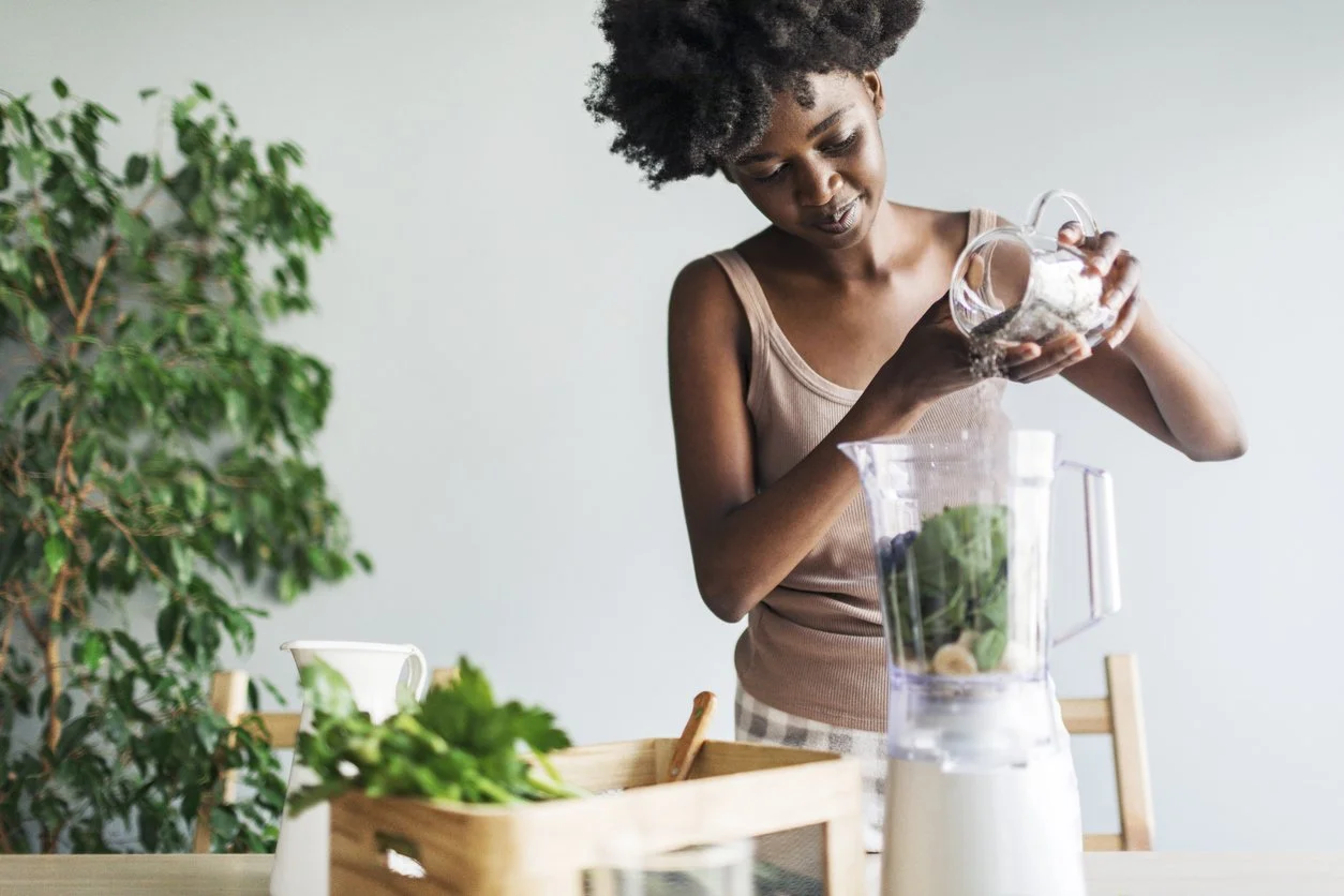 A perimenopausal woman is making a healthy smoothie in a blender