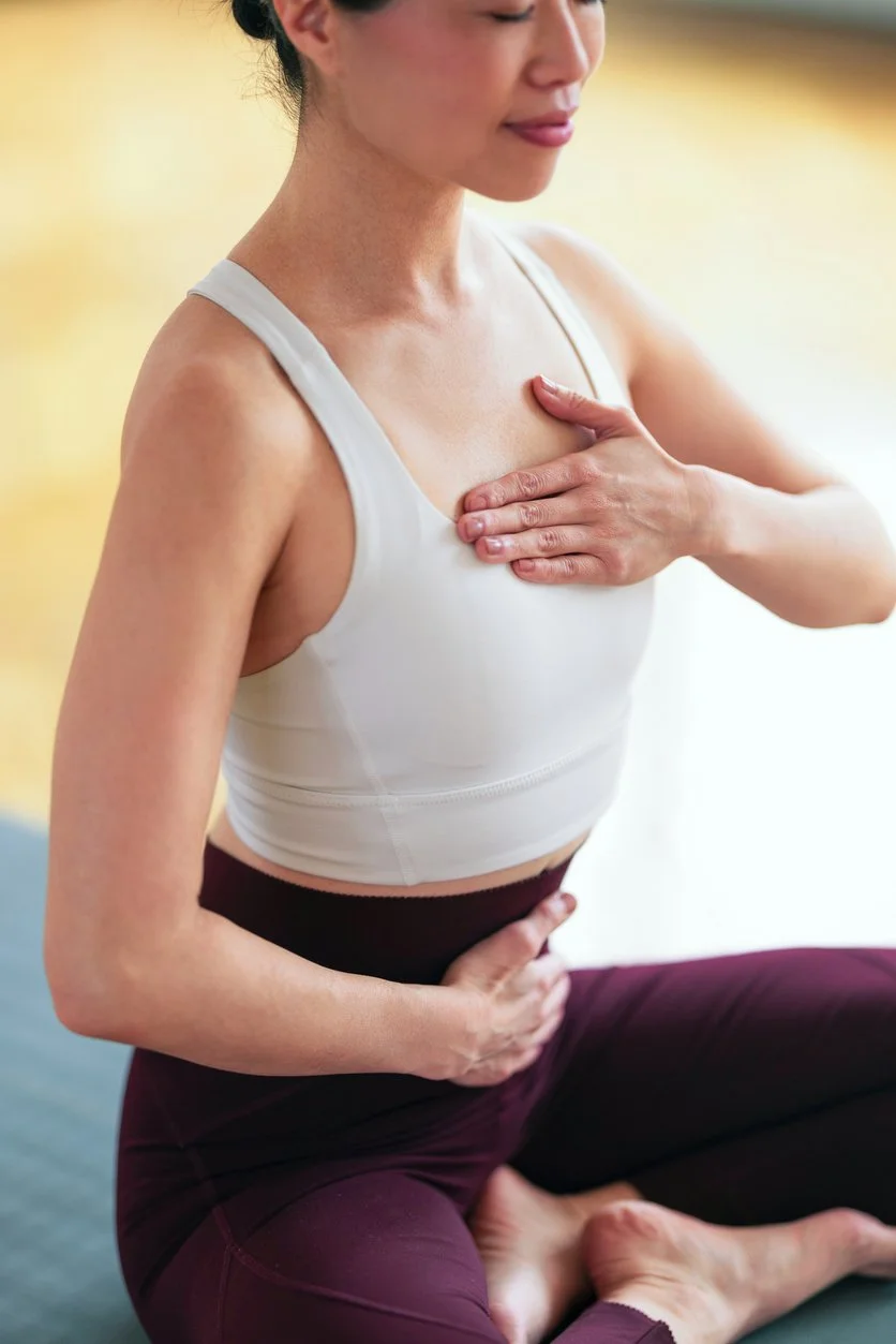 Calm woman in white top and burgundy leggings on yoga mat