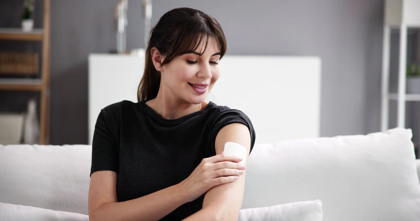 Smiling woman wearing a hormone replacement therapy patch on her arm