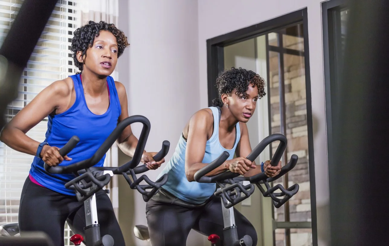 Twin sisters working out together on exercise bikes