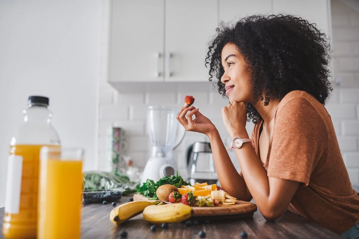 Smiling woman holding a strawberry in her kitchen