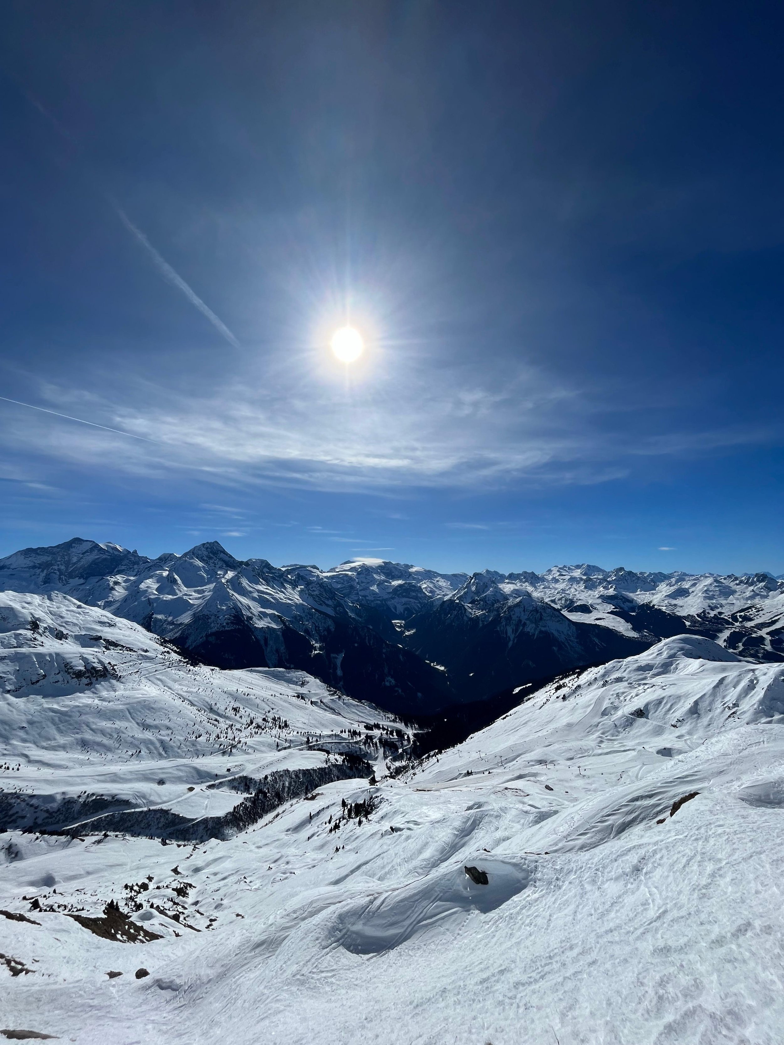 Paysage de montagnes enneigées sous un ciel bleu avec le soleil brillant