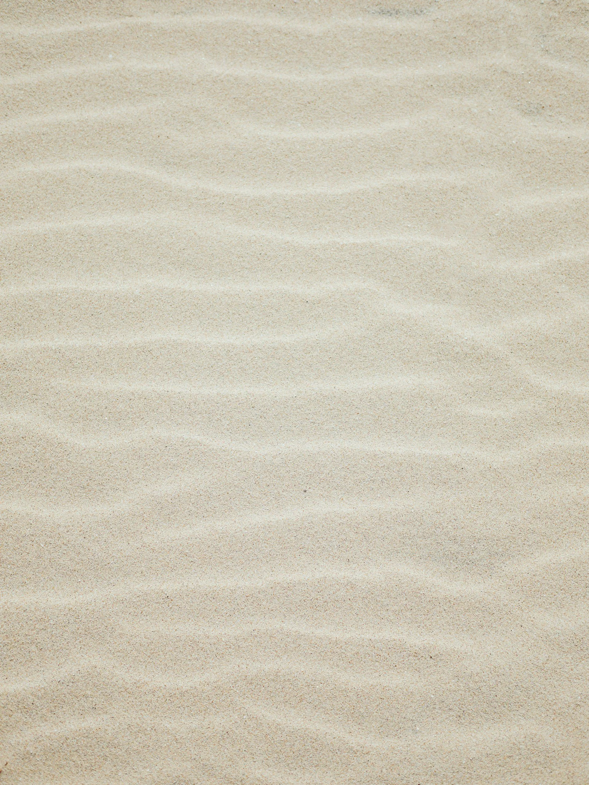 Close-up of beige sand with wavy patterns