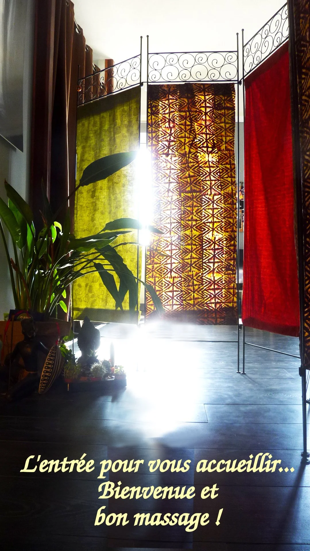 Une porte d'entrée décorée avec des rideaux colorés (jaune, à motifs, rouge), laissant passer la lumière du soleil brillante. À gauche, il y a une plante verte en pot et des statuettes ou décorations.