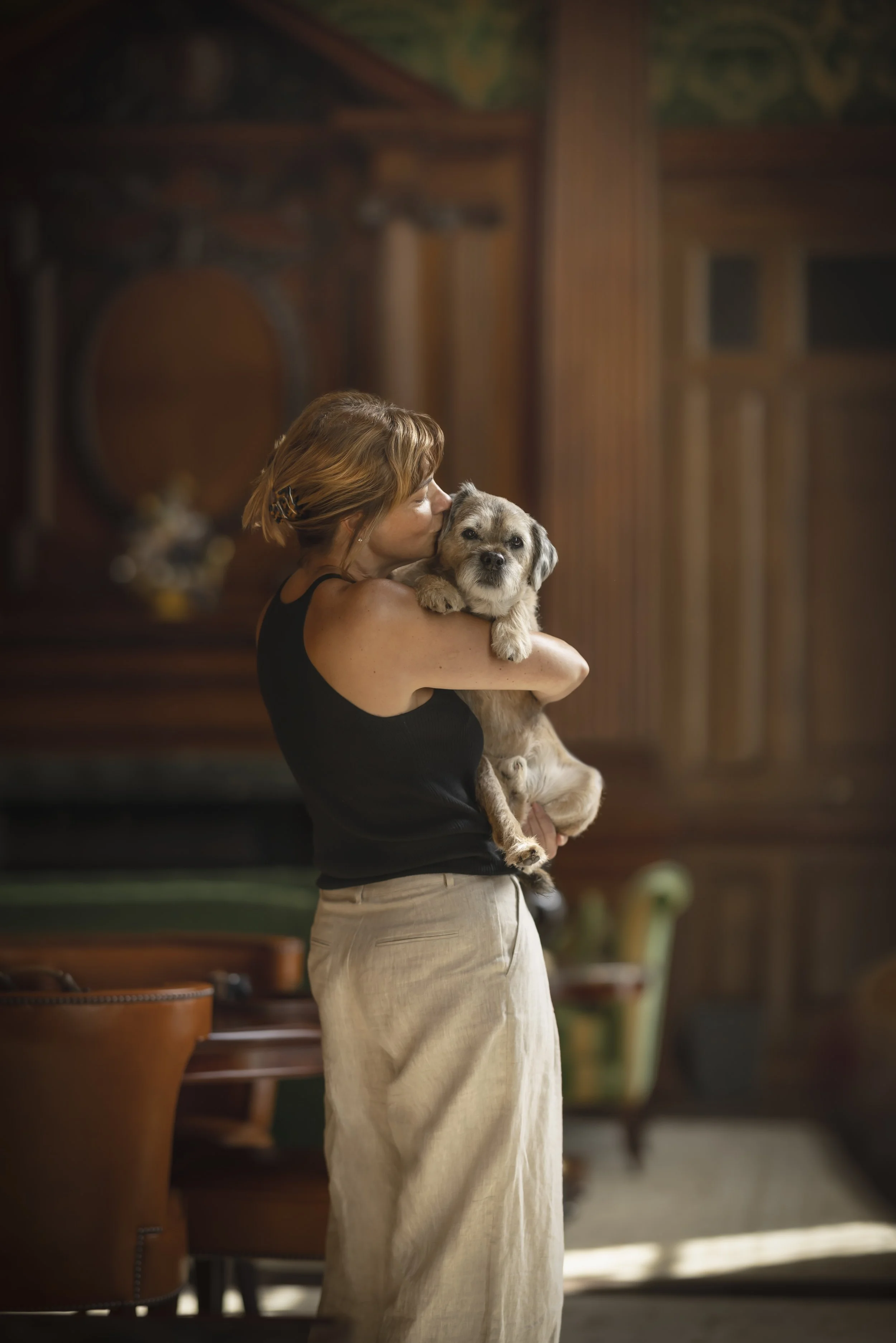 Woman holding and kissing her dog in their suite at Raffles London at The OWO during a private dog portrait session photographed by Andrew Raven.