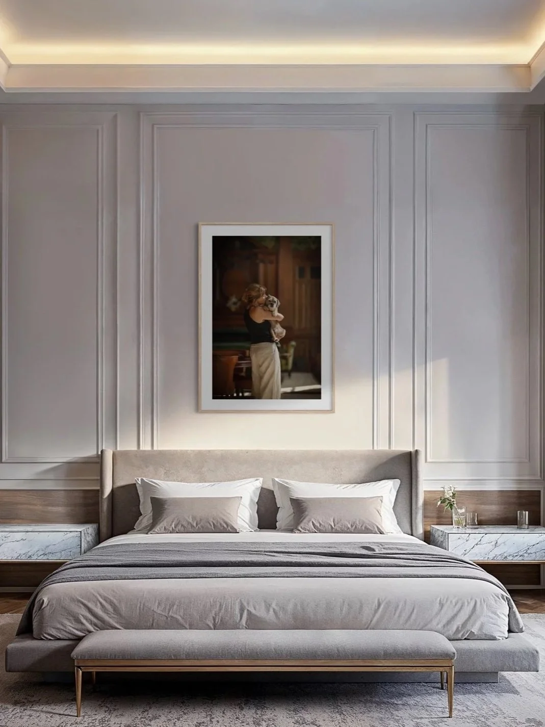 Framed fine art portrait of a woman holding her dog, originally photographed at Raffles London at The OWO by Andrew Raven, displayed above a bed in a contemporary interior.