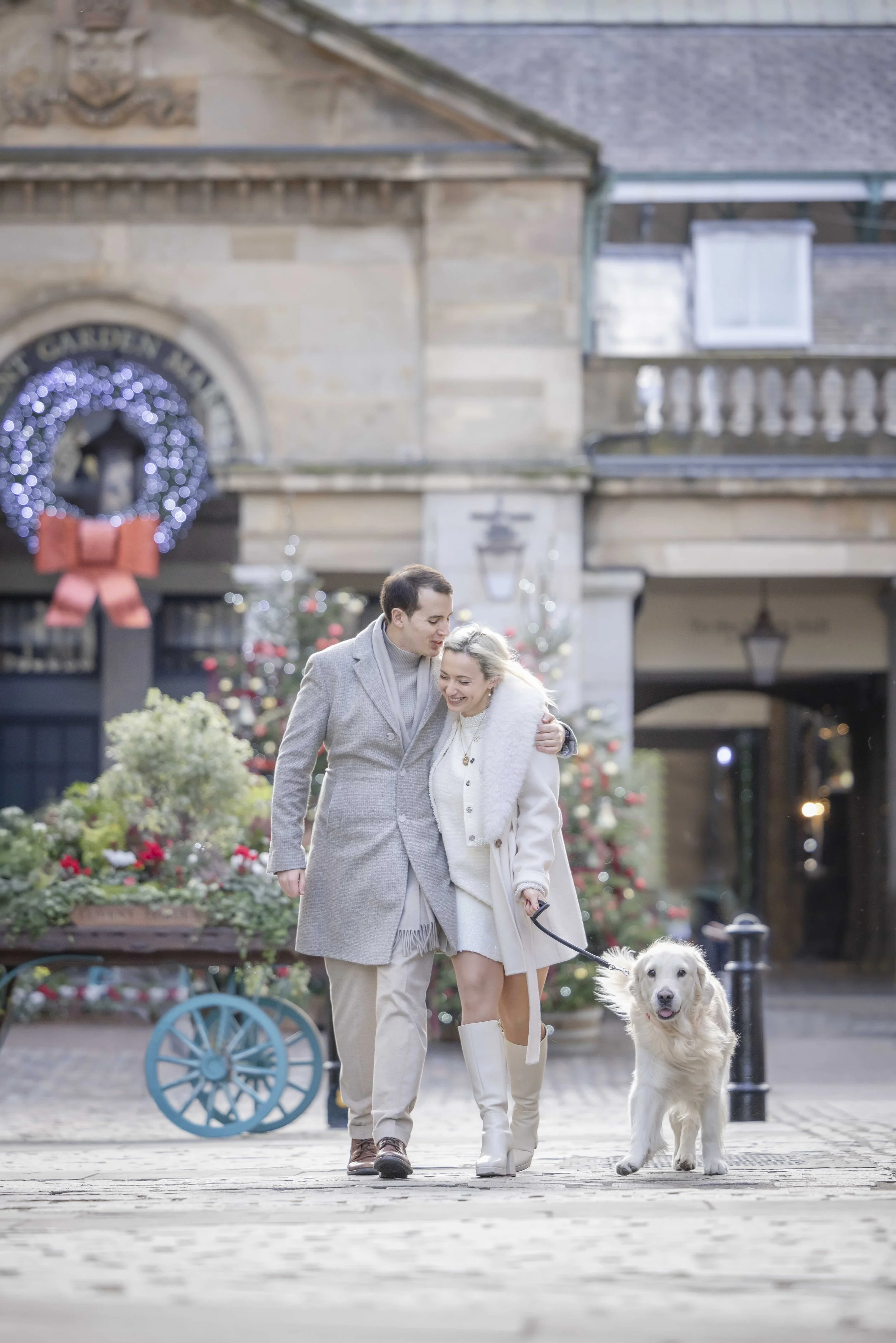 Couple walking with their Golden Retriever through the Christmas decorations in Covent Garden during a London dog photoshoot.