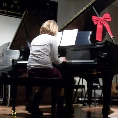 Child playing piano decorated with a red ribbon