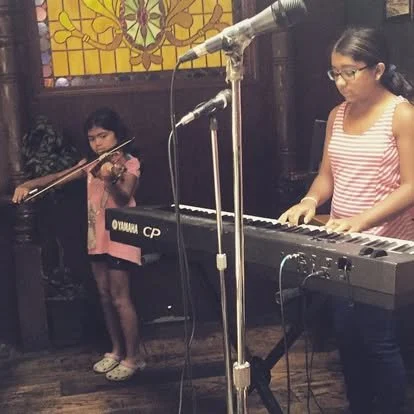 Piano and voice student performing at an event with her sister accompanying on the violin. Music arrangement by Ms. Brown and performed live for the Dogtown Street Musician's Festival