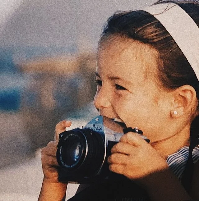 Niña sonriente con una cámara fotográfica antigua.