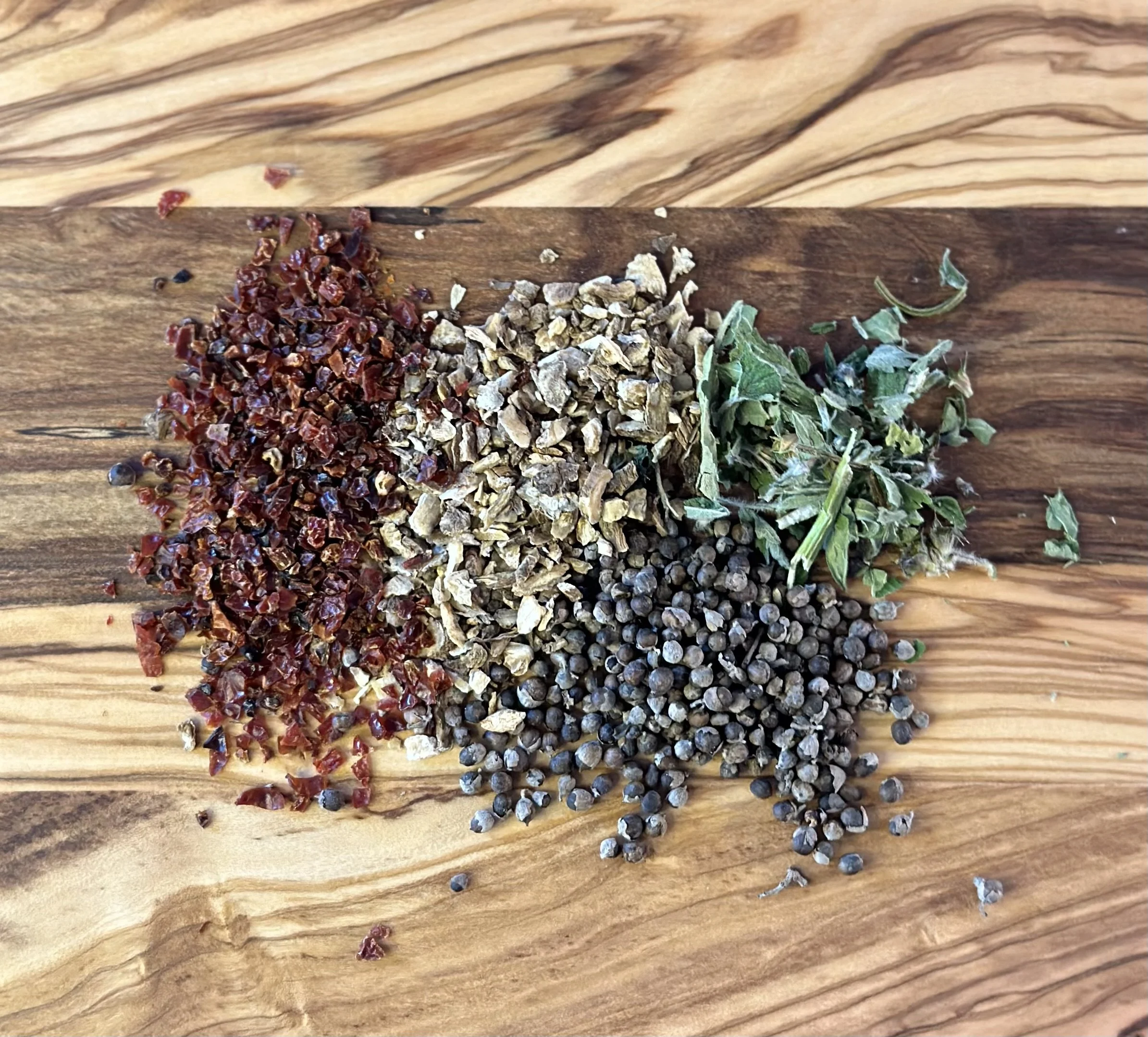 Three different types of Chinese herbal medicine arranged in parallel lines on a wooden surface.