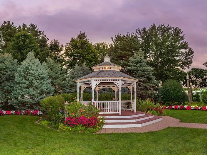 dusk photo of white gazebo in front of pine trees