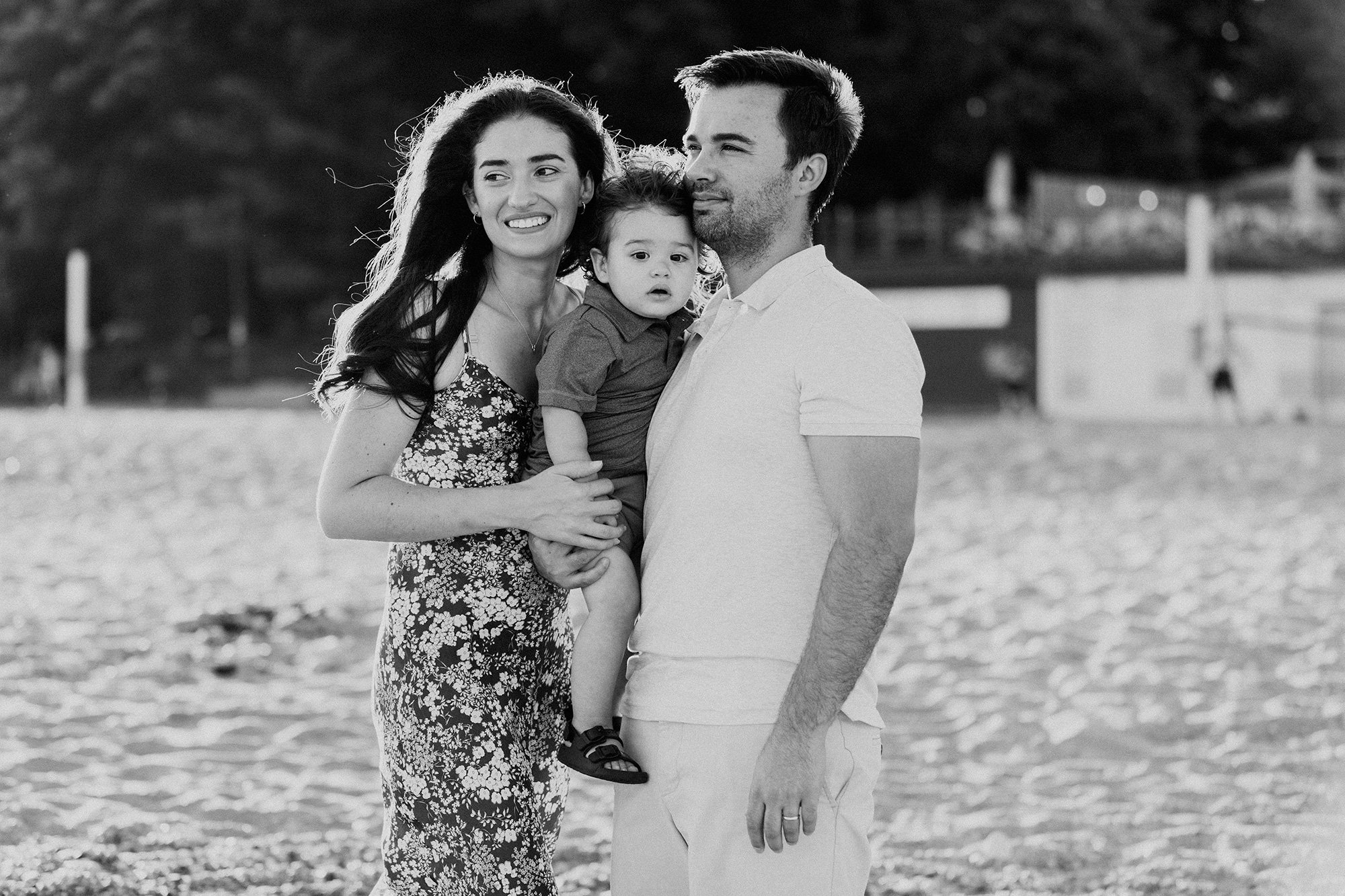 Family photo session on a beach in Toronto. Mom, dad and toddler looking out to the lake.