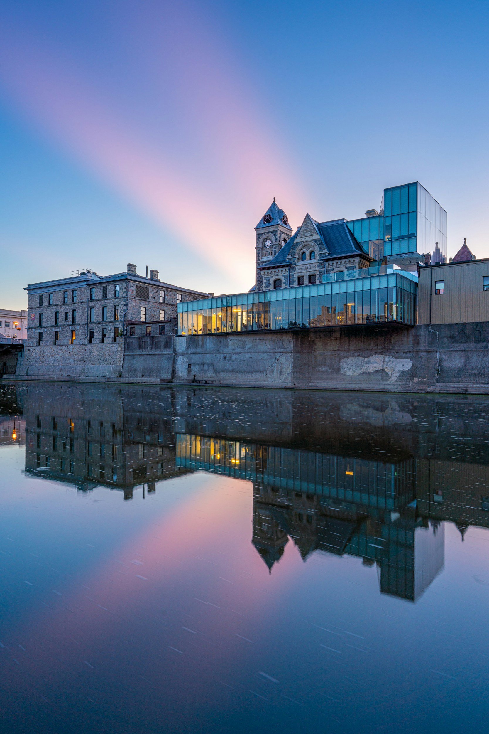 Reflection of buildings and a blue sky with pink clouds on water