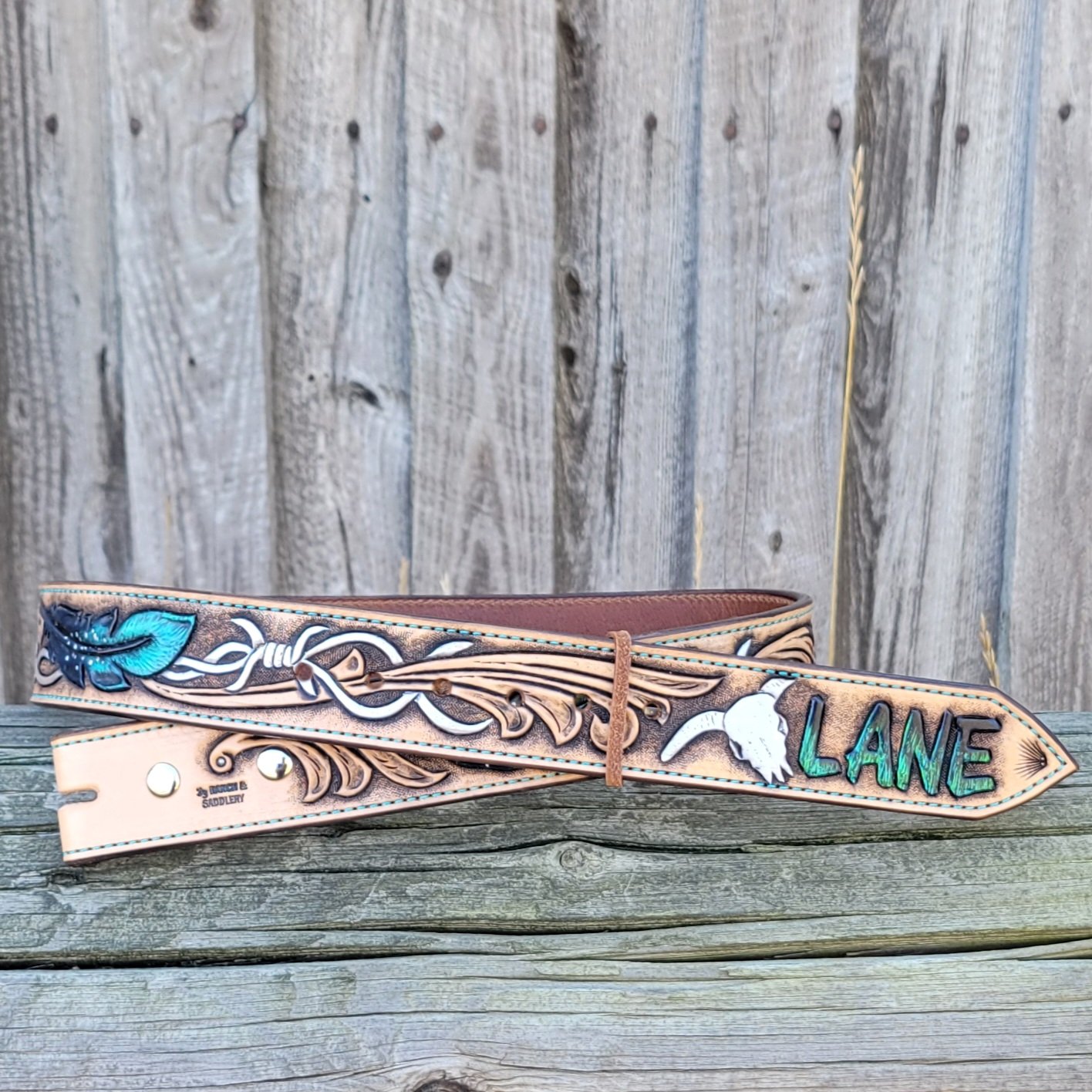 Custom belt hand tooled with barb wire and feathers.