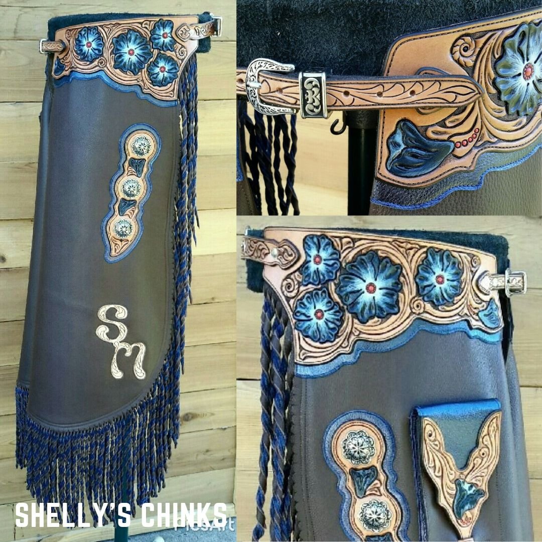 Shelly's custom chinks were designed around the color sapphire. The custom chinks include two-tone twisted fringe, painted floral tooling, phone pocket, and inlayed initials.