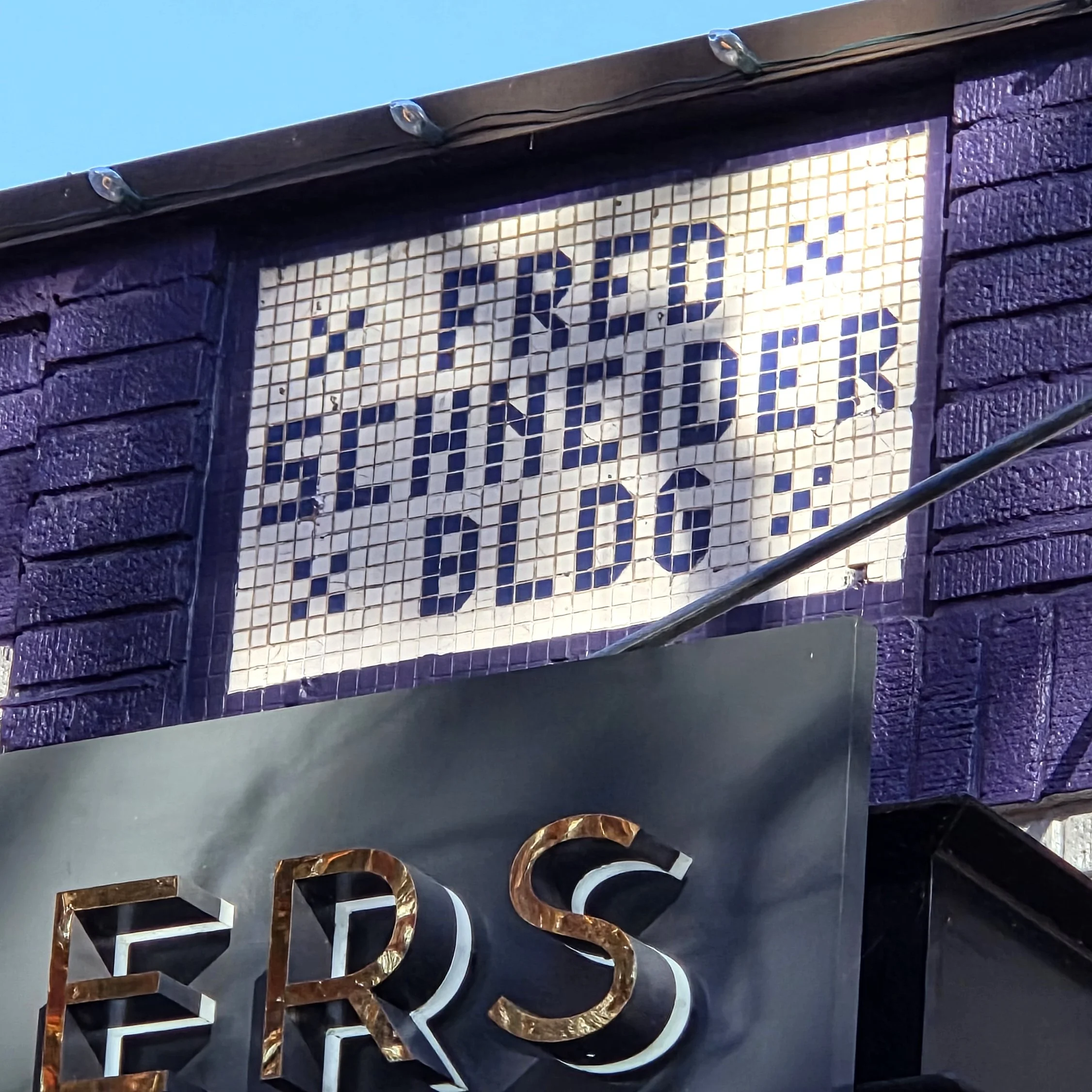 Photo of the top of a building that has an oldschool tile sign that says "Fred Schneider Bldg"