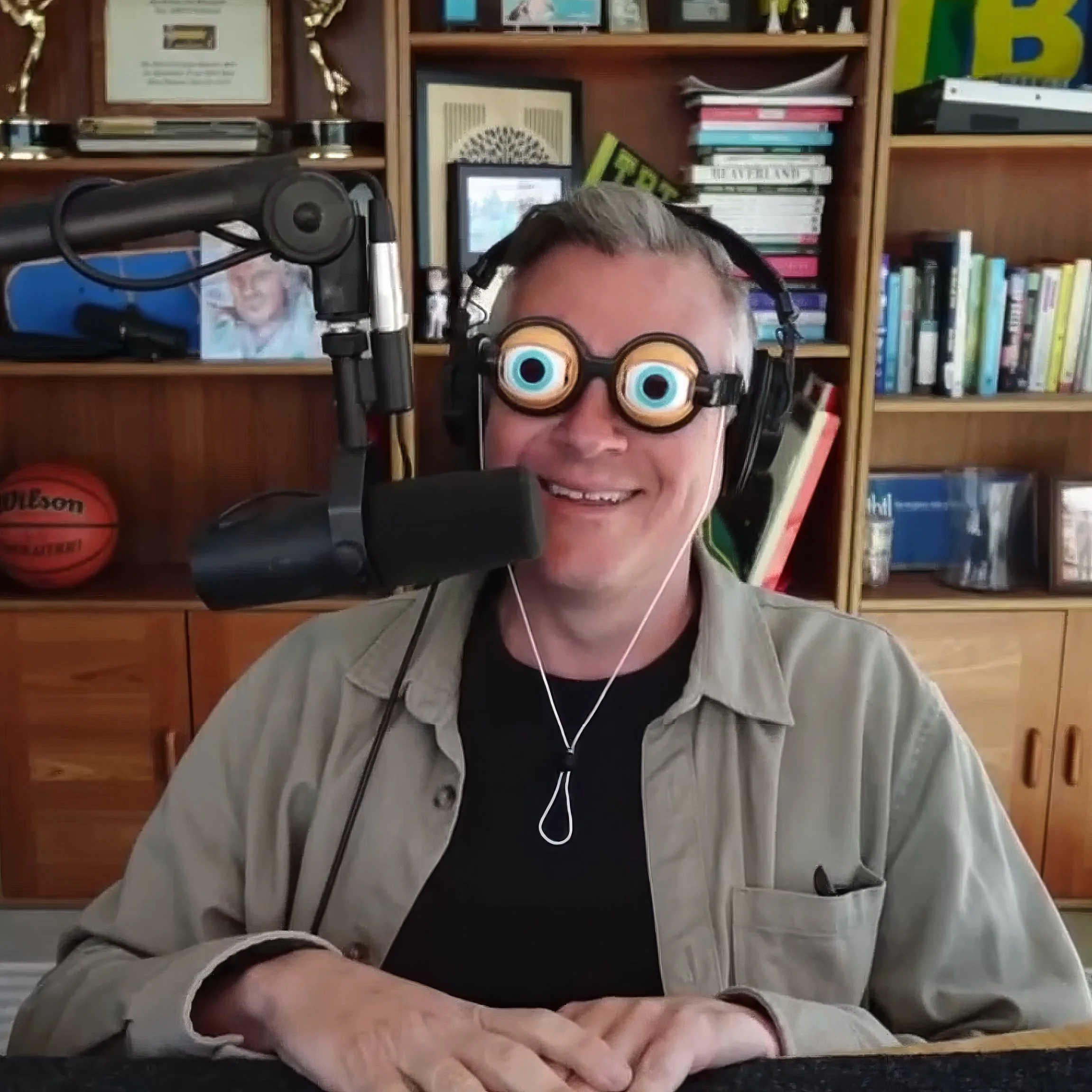 Photo of Luke sitting behind the mic in his studio wearing novelty glasses with big bulging eyes