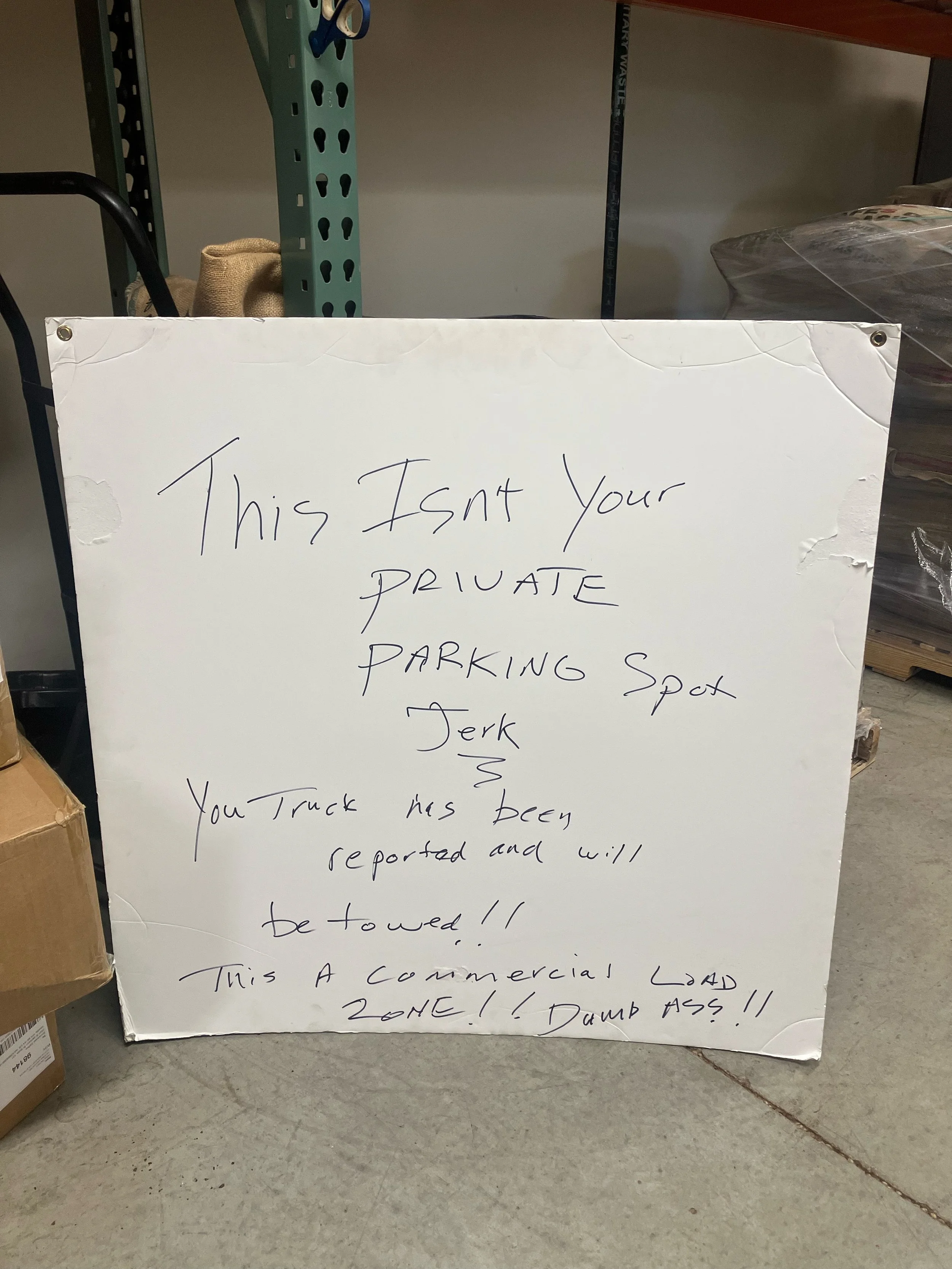A picture of a sign that reads "This isn't your private parking spot jerk. You truck has been reported and will be towed!! This is a commercial load zone! Dumb ass!!"