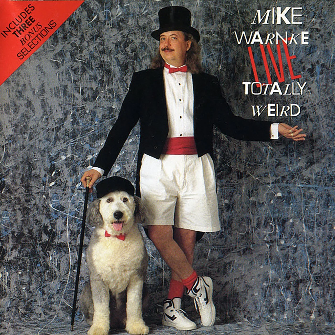 Album cover for comedy album "Mike Warnke LIVE Totally Weird". It shows him wearing a tuxedo with shorts next to a white poodle wearing a hat.