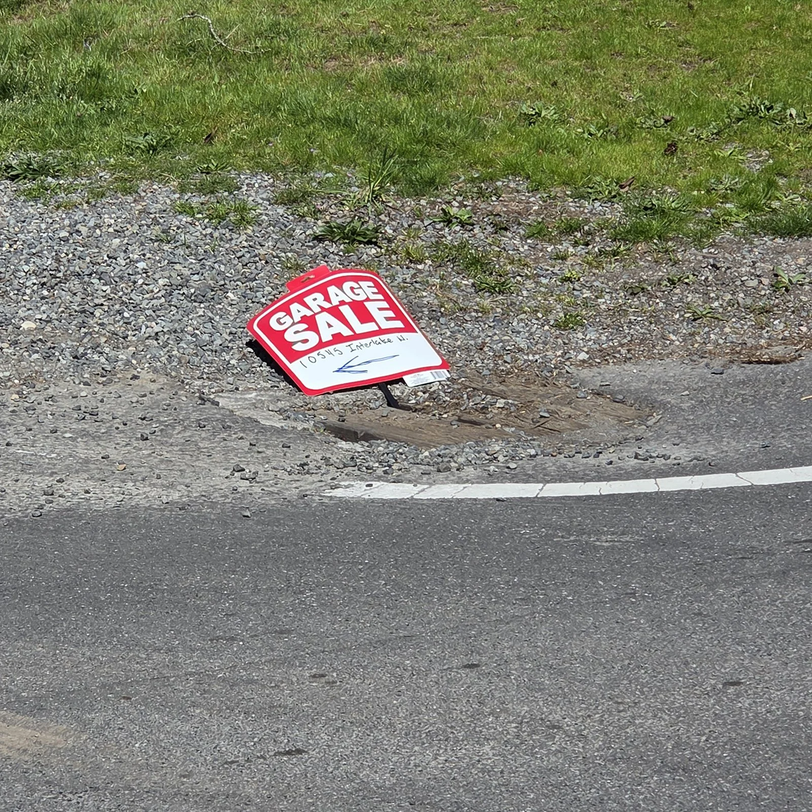A crumpled garage sale sign that has been thrown on the ground at a street corner