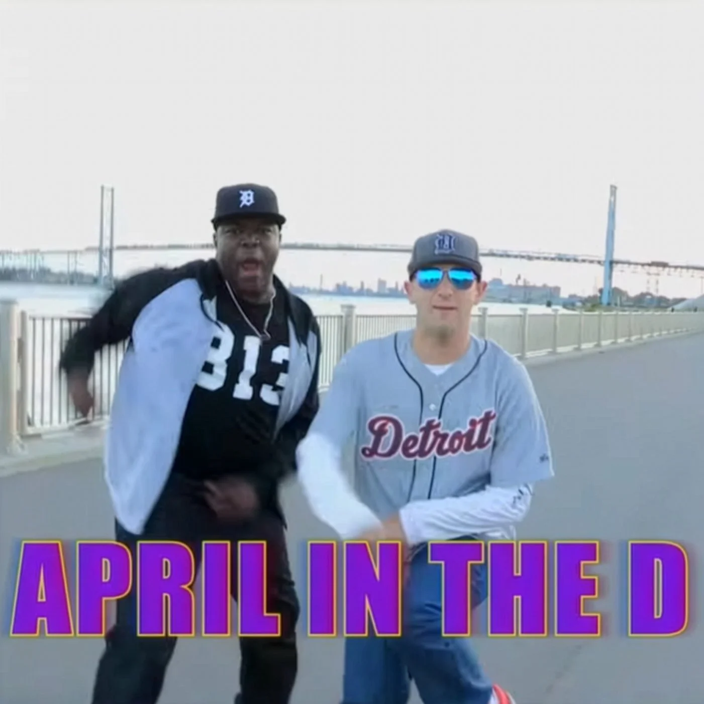 Screen cap from The Detroiters showing Sam and Tim in Detroit garb, outside, rapping. The words APRIL IN THE D are emblazoned across the screen