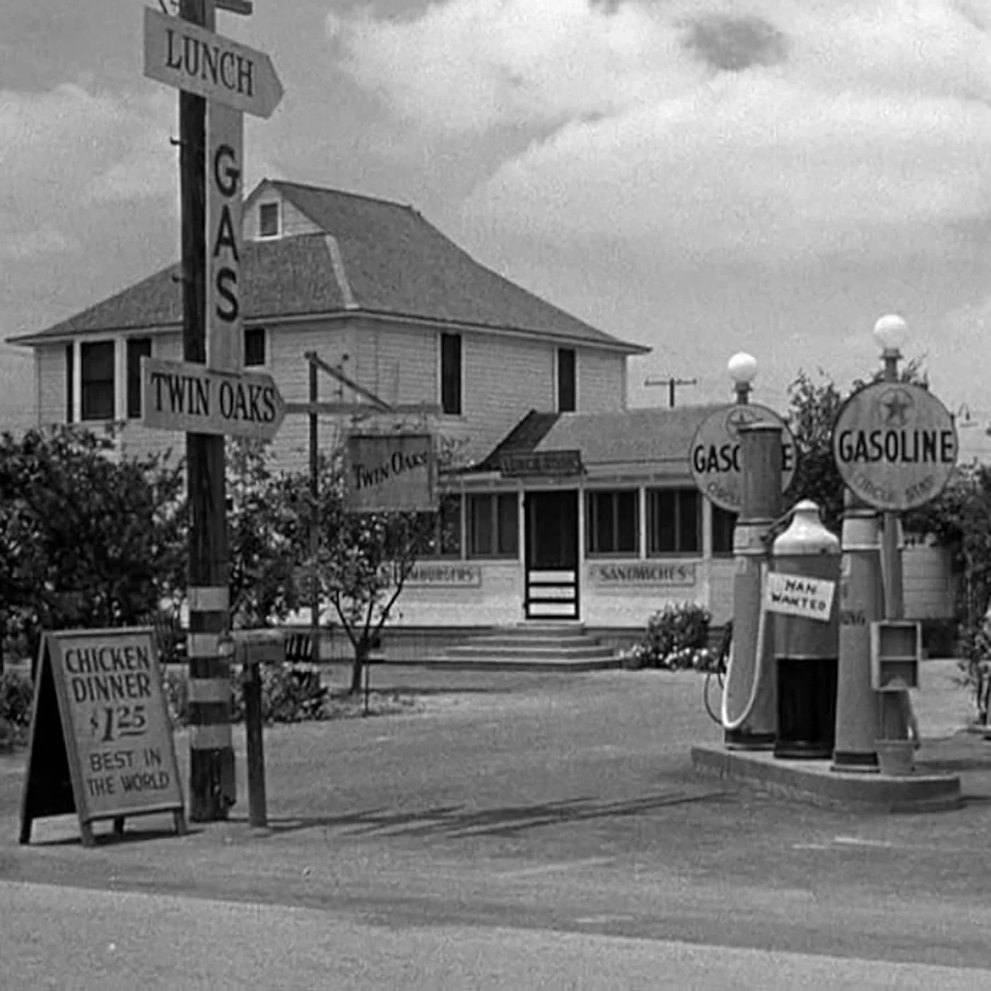 Image of the gas station / diner from the movie "The Postman Always Rings Twice" -- Exterior shot, black and white, of 1940s era gas pumps, signs, and small house that runs the business.