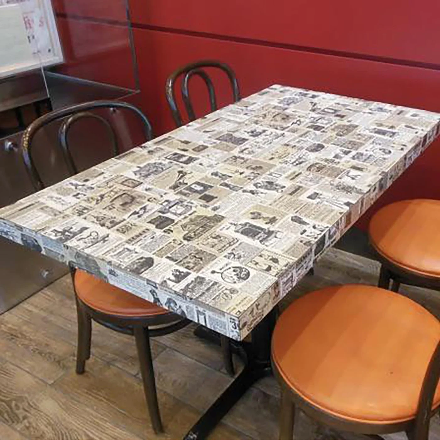 Photo of a table that they used to have in Wendy's in the 1980s and 1990s. It's designed to look like it's covered in old newspaper ads from the early 1900s.