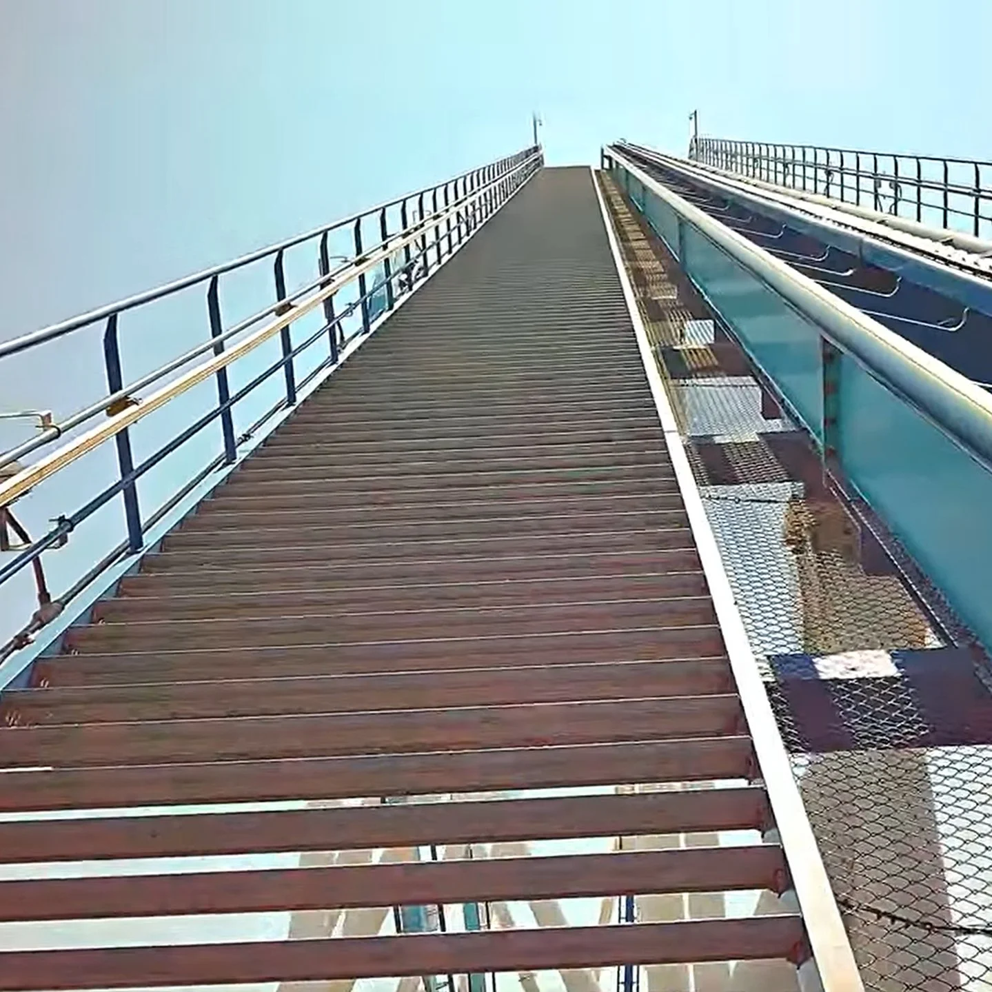 Still shot from a video showing stairs on a roller coaster, running along the side of the tracks, uphill on the first big hill