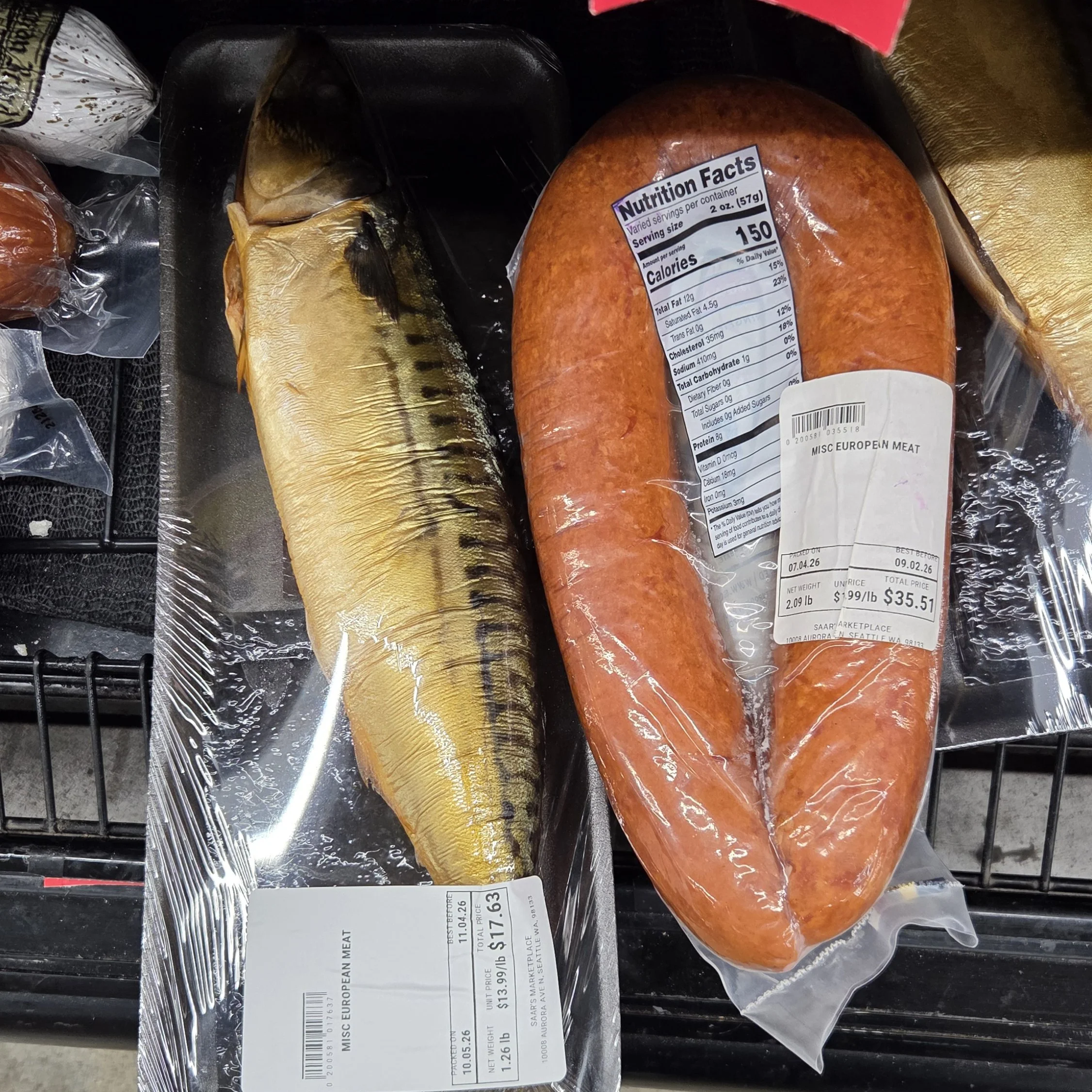 Photo of a huge kielbasa sausage in it's packaging next to a raw fish (in simple packaging)