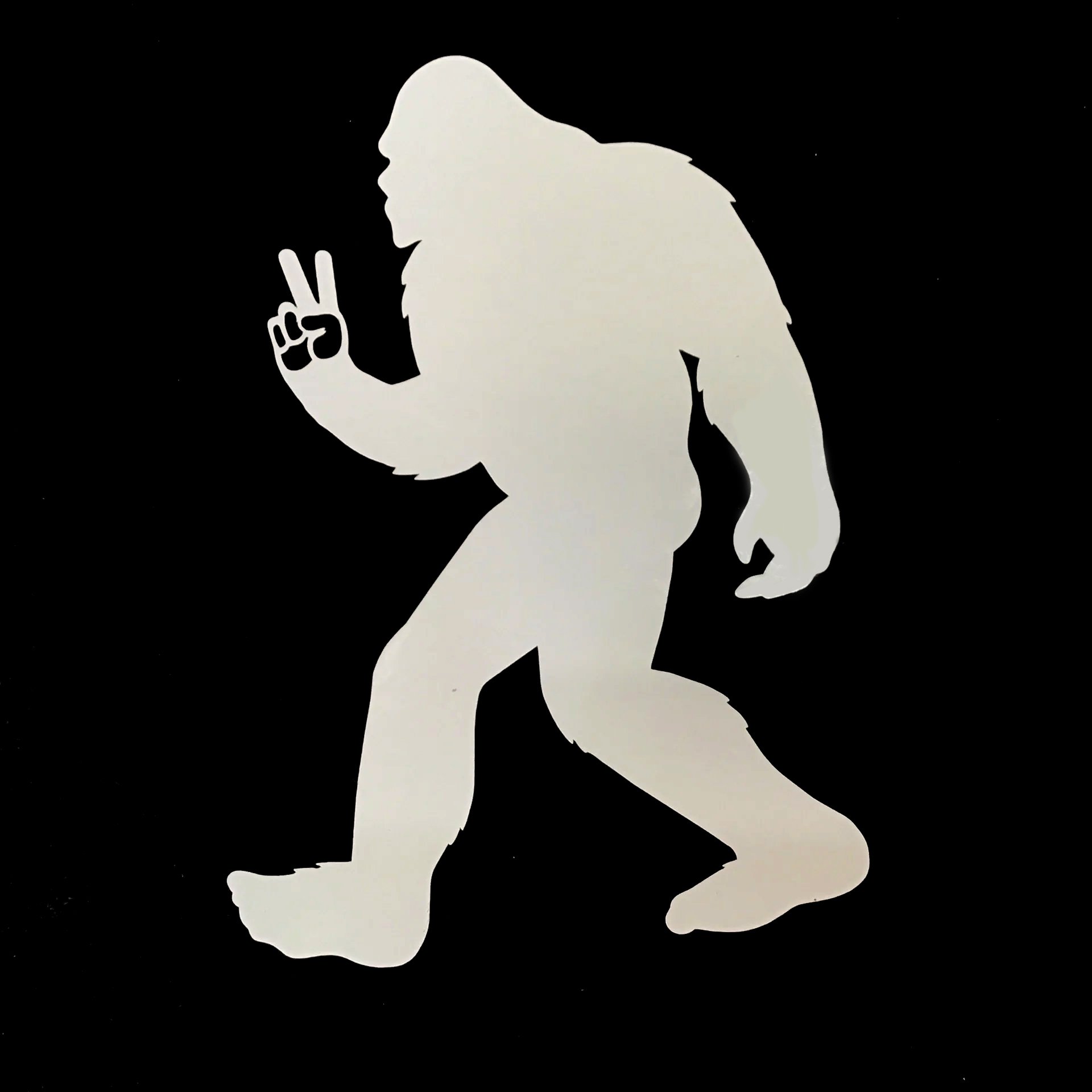 Illustration of a silhouette of a sasquatch walking right-to-left and holding up a peace sign with two fingers