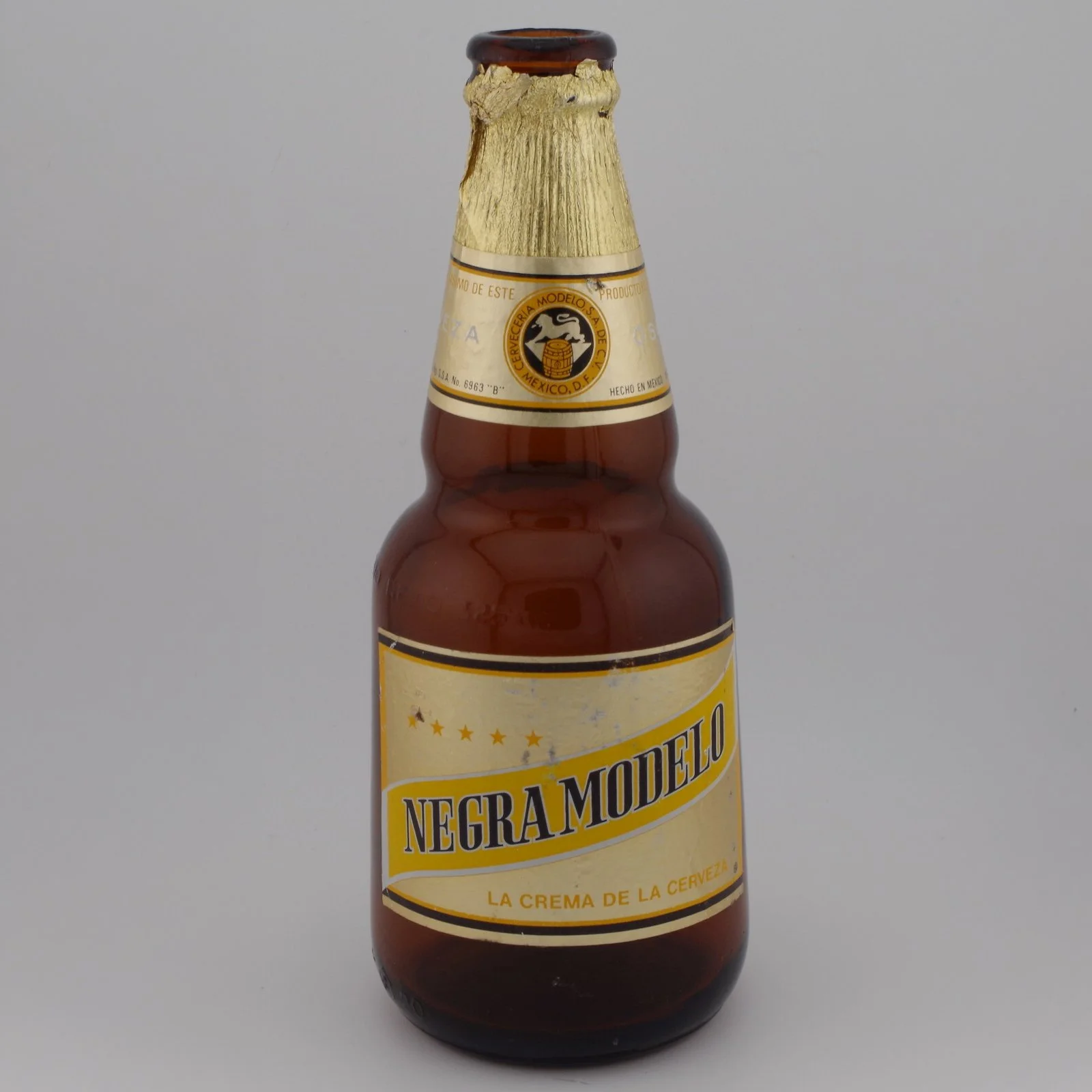 Stock photo of a bottle of Negra Modelo beer with it's cap removed and gold foil torn at the top