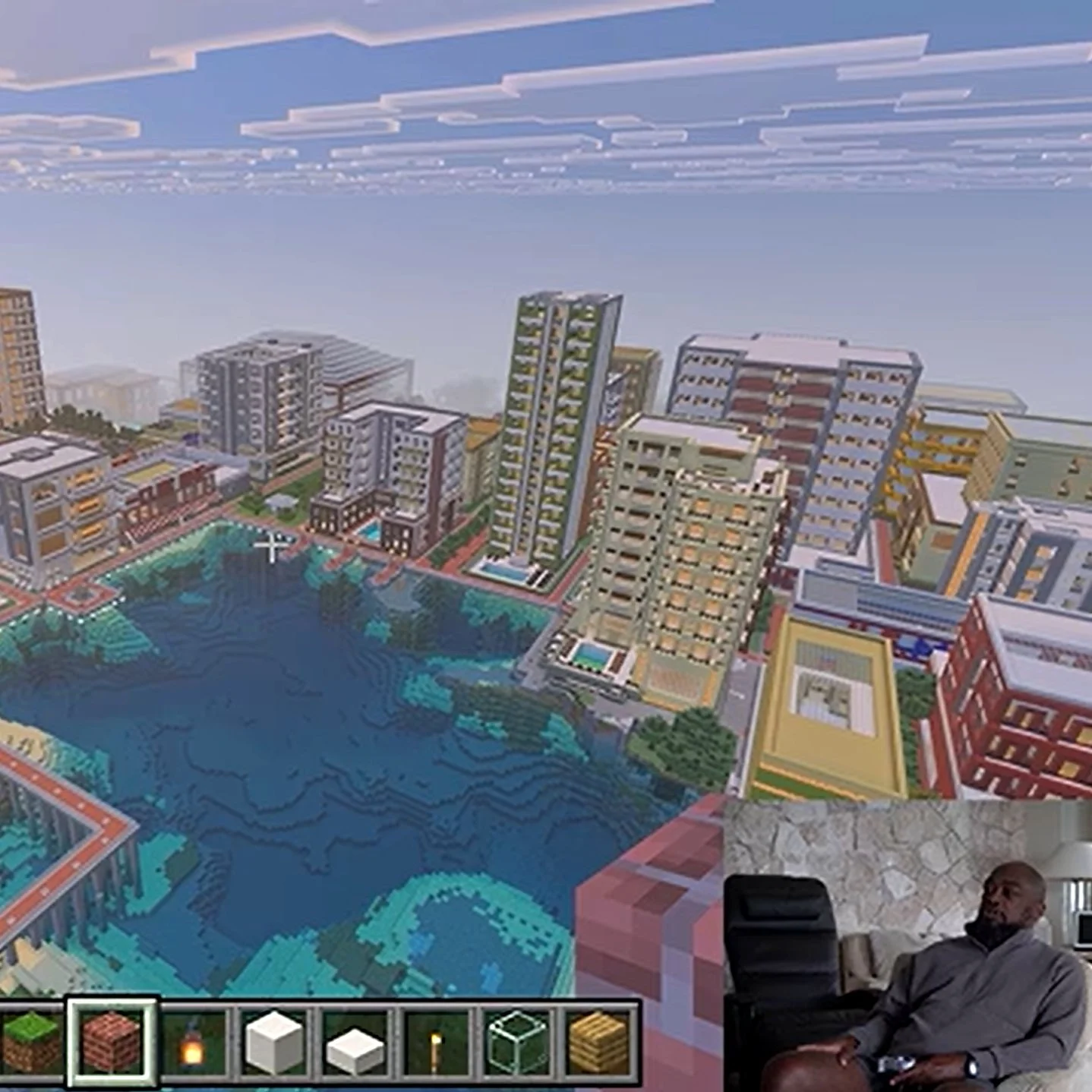 Overhead view of a large city in Minecraft made by Mike Tomlin, who is seen in the bottom right corner of the screen, holding an xbox controller