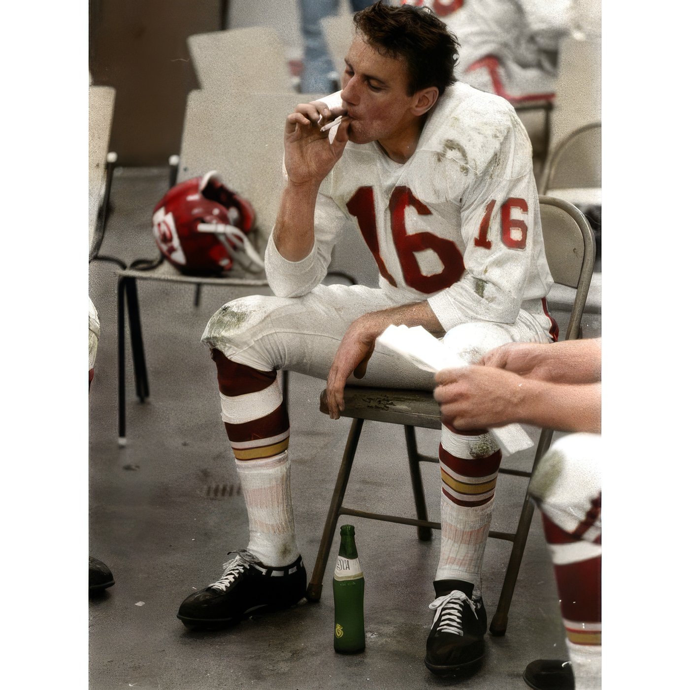 Photo of NFL player Len Dawson in uniform immediately after Super Bowl 1 smoking a cigarette while sitting on a folding chair