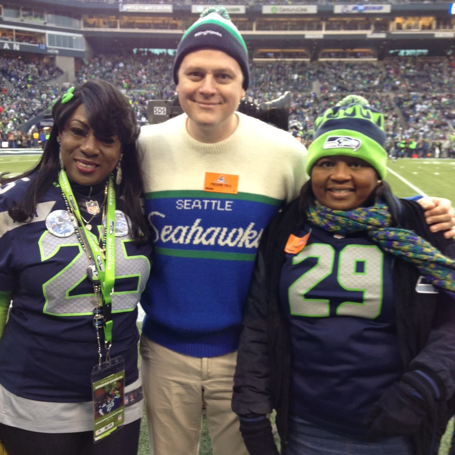 Photo of Luke on the sidelines of a Seahawks game with his arms around the shoulders of two people, one of whom is marshawn lynch's mom