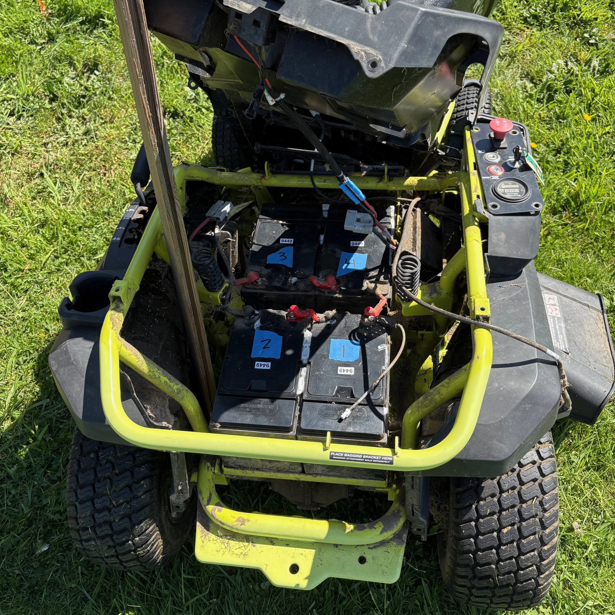 Photo of an electric lawnmower opened up showing its four batteries inside