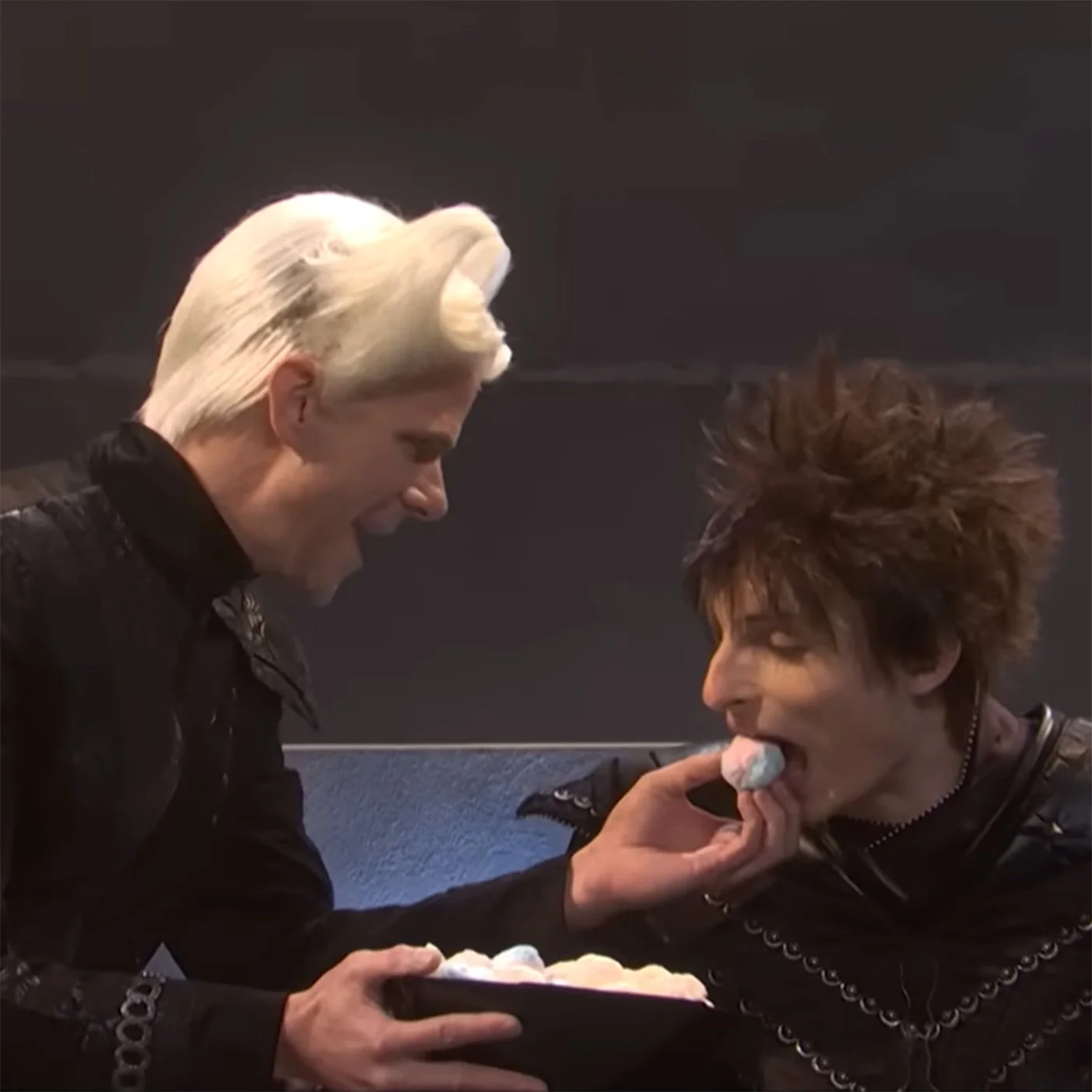 Screenshot from SNL depicting a space emperor being fed a thing that looks like a donut ball by a space servant