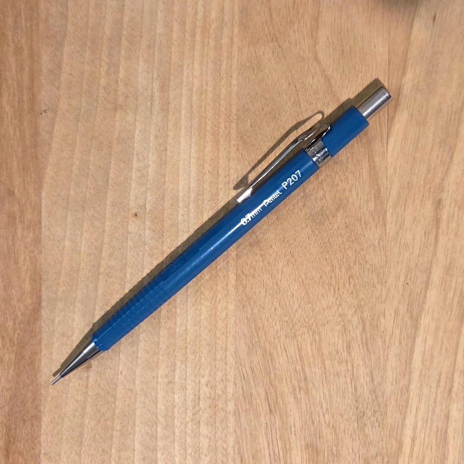 Photo of a light blue mechanical pencil sitting on a wooden surface