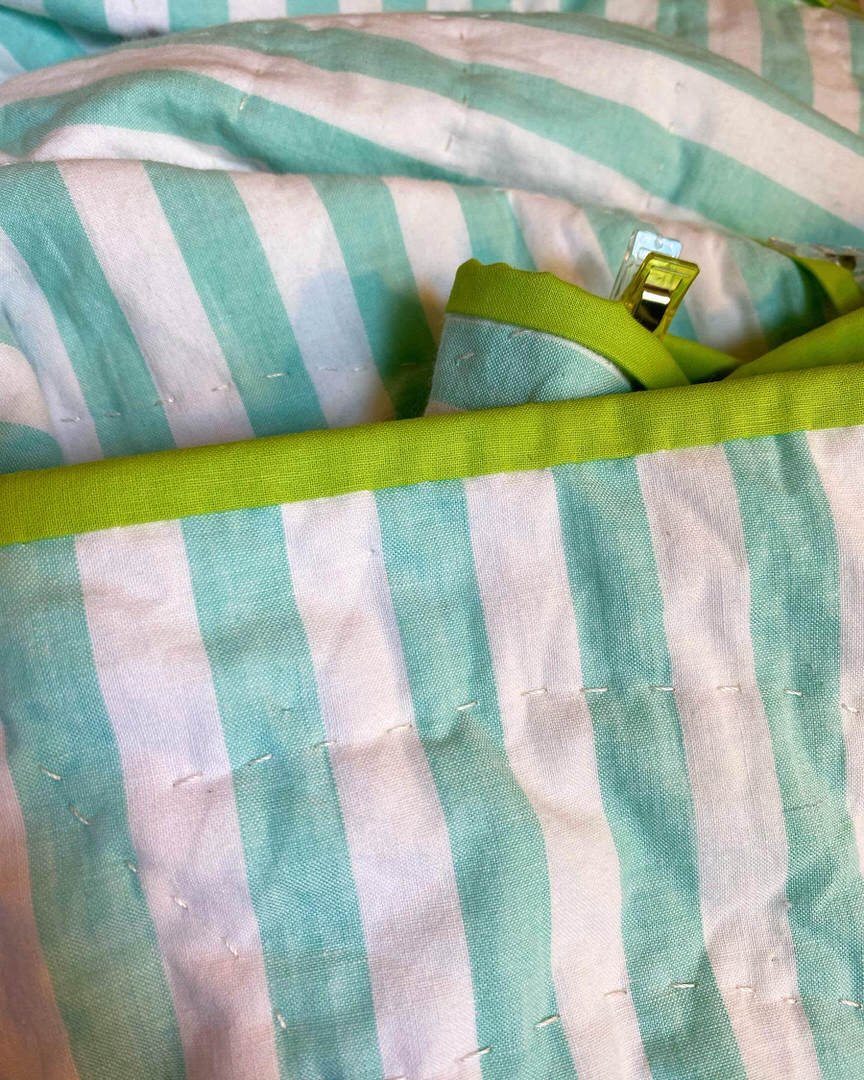 The chartreuse binding contrasting with the aqua striped quilt back