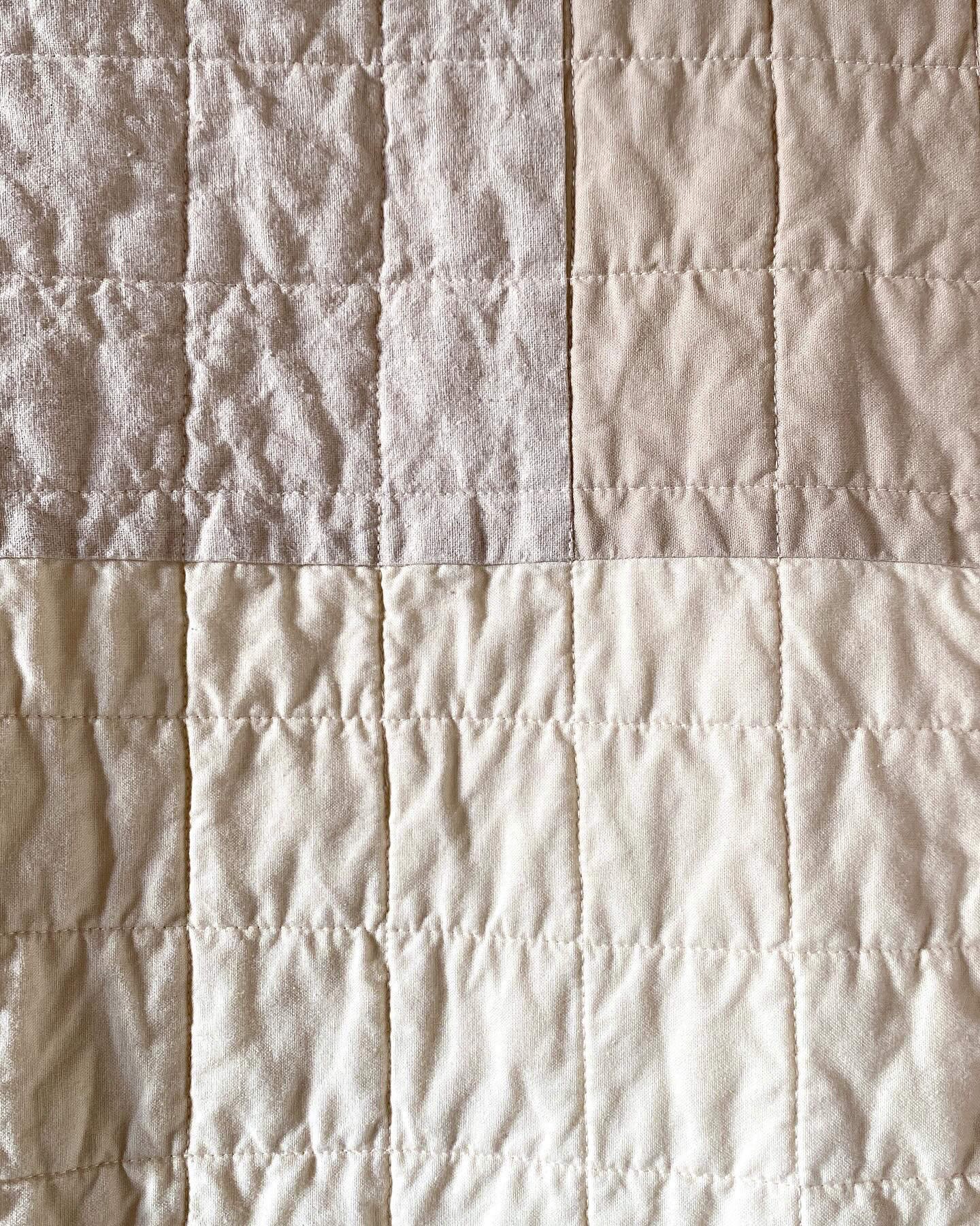 Close up of the subtle white quilted grid, set into the tan patchwork of the quilt top.
