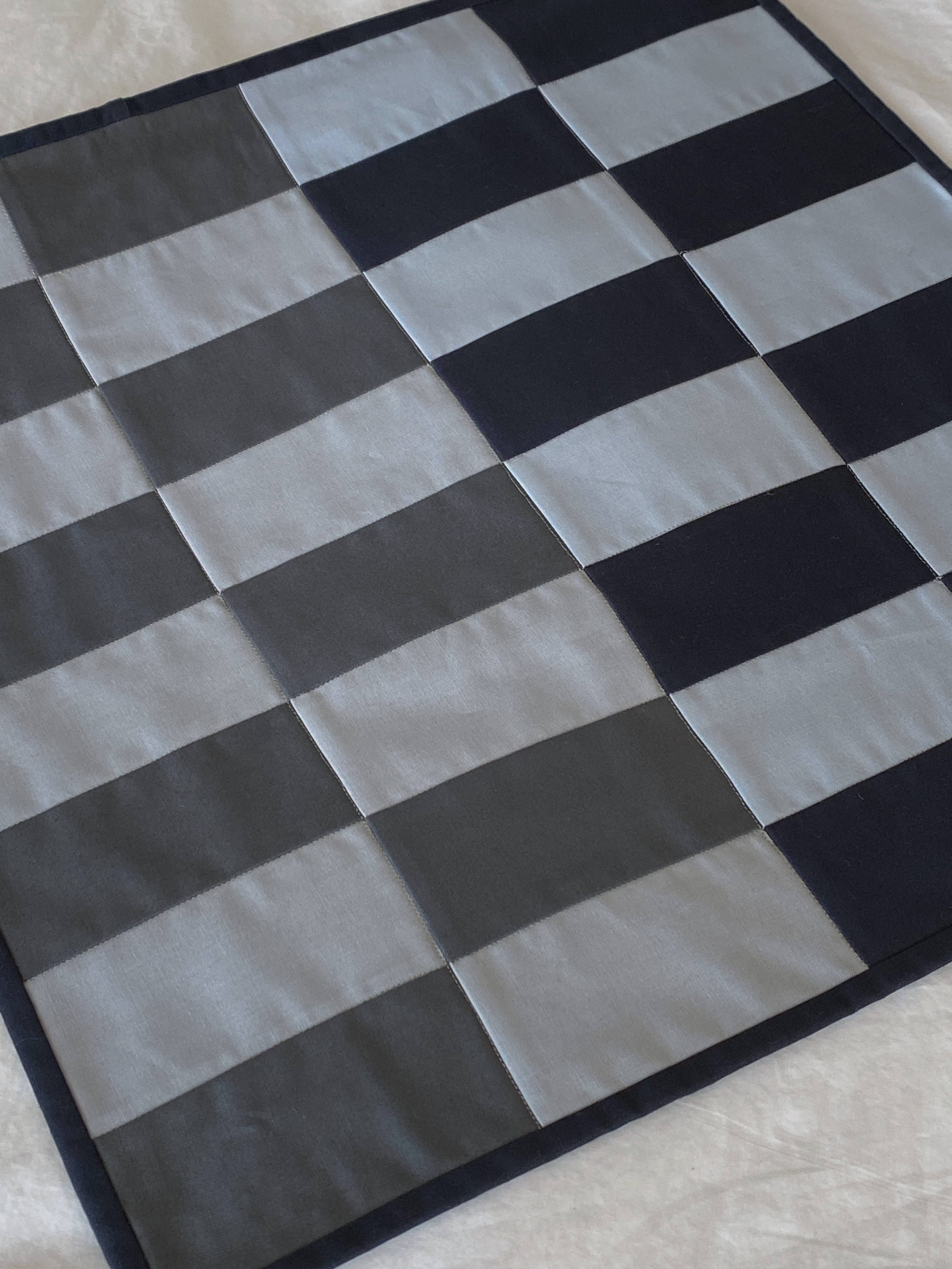Close up of the front of the quilted patchwork, laying relatively flat, in tints and shades of unsaturated blues