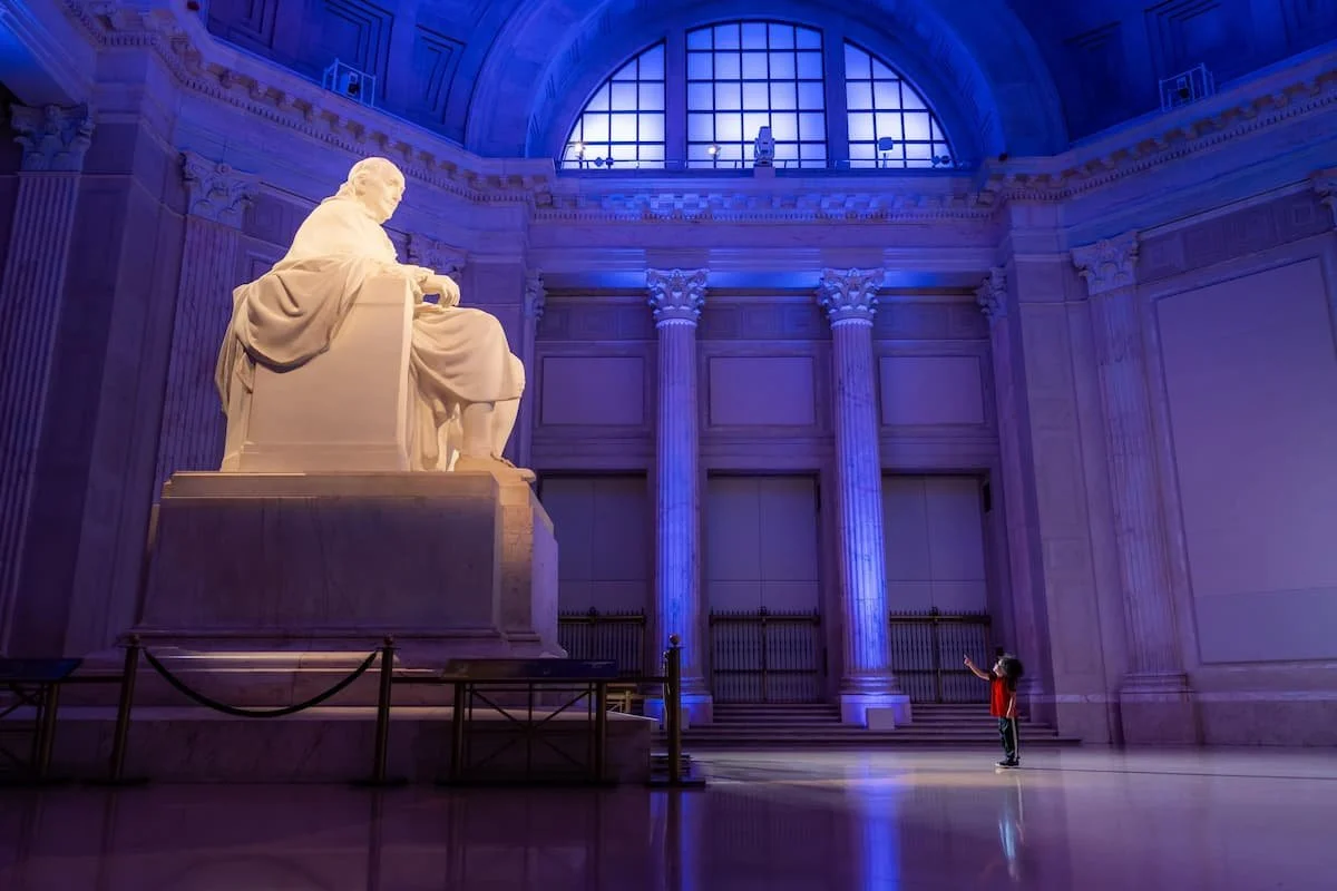 A young child pointing up at a statue of Ben Franklin inside the Franklin Institute in Philadelphia, PA