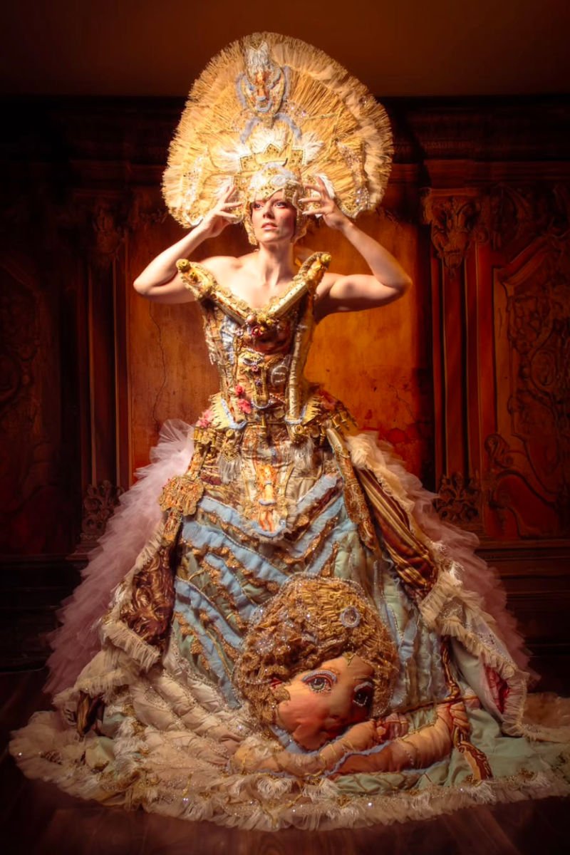 A woman dressed in a fancy gown and a large hat, showcasing a refined and fashionable appearance.