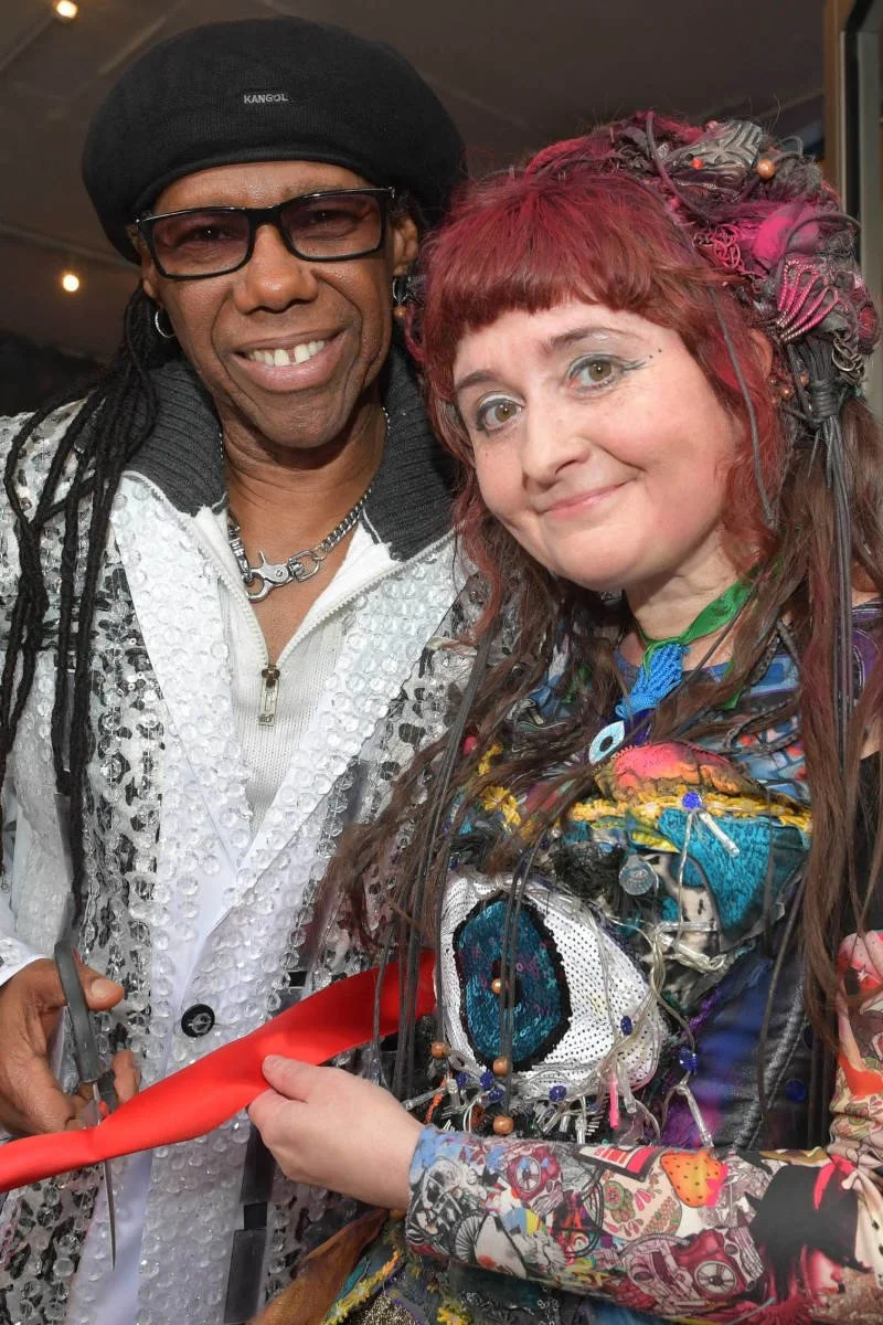Nile Rodgers and Claire Garvey hold a red ribbon together, symbolizing unity and celebration