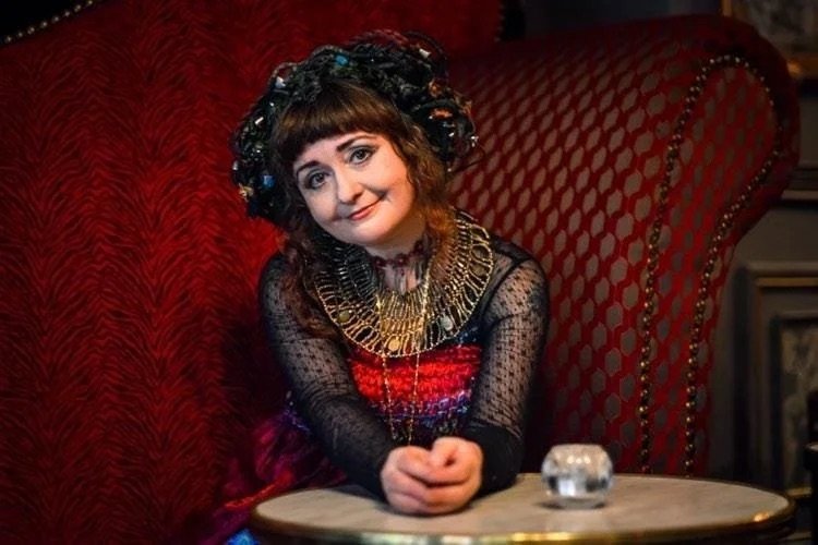 A woman in a red dress sits elegantly on a chair, showcasing Claire Garvey's sustainable Irish fashion design.