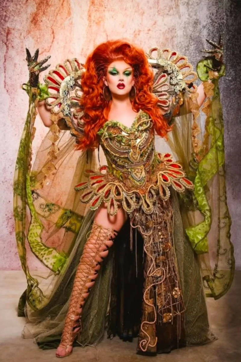 Elle Vosque from RuPaul's Drag Race UK, showcasing her vibrant red hair and intricate costume design by Claire Garvey