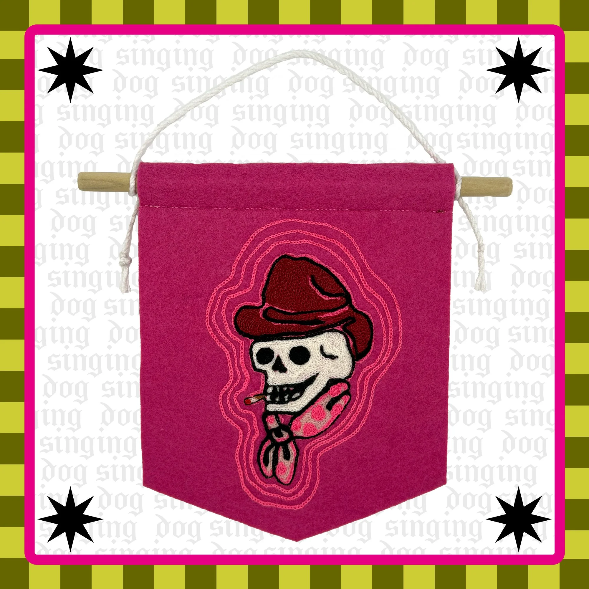An embroidered felt wall hanging depicting a smoking cowboy skull. Known as 'Crazy Sal', this chainstitched skull is a common motif in American Traditional tattoo design. The colors are mostly pink and white. 
